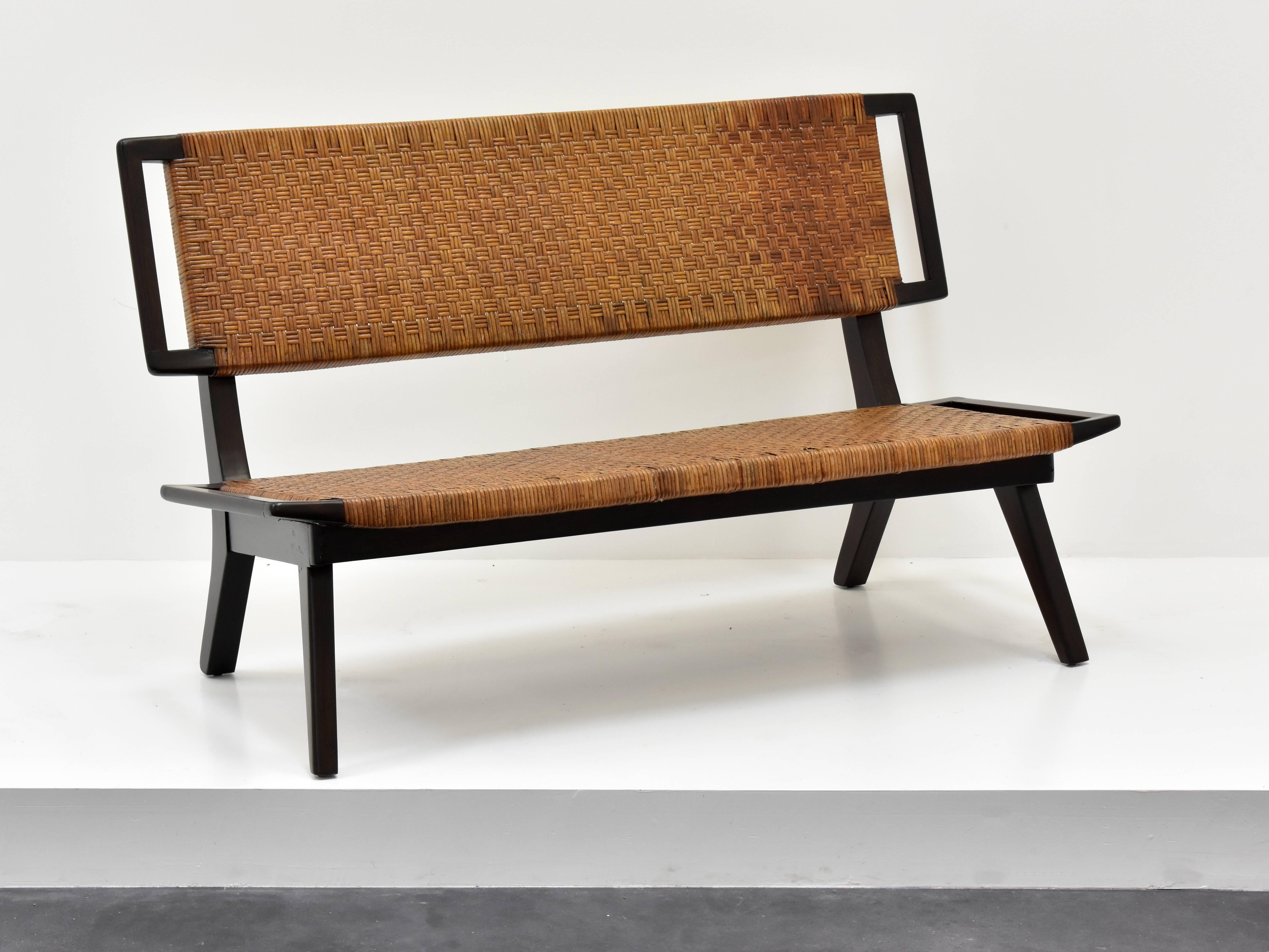 A settee, bench or small sofa in the style of Paul László for Glenn of California. Dark stained mahogany and original woven rattan.

Paul László is considered among the most important California-based interior designer/architects of all time. At the