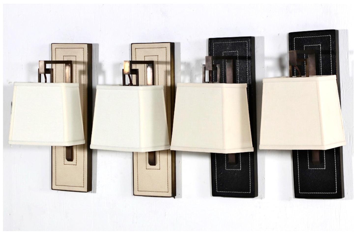 Shown are two pairs of the very desirable Paul Marra Brass and Leather Art Deco/Moderne style wall sconces. The sconces show the design influence of Jacques Adnet in the stitched leather detailing of the sconces' back plates. The design is further
