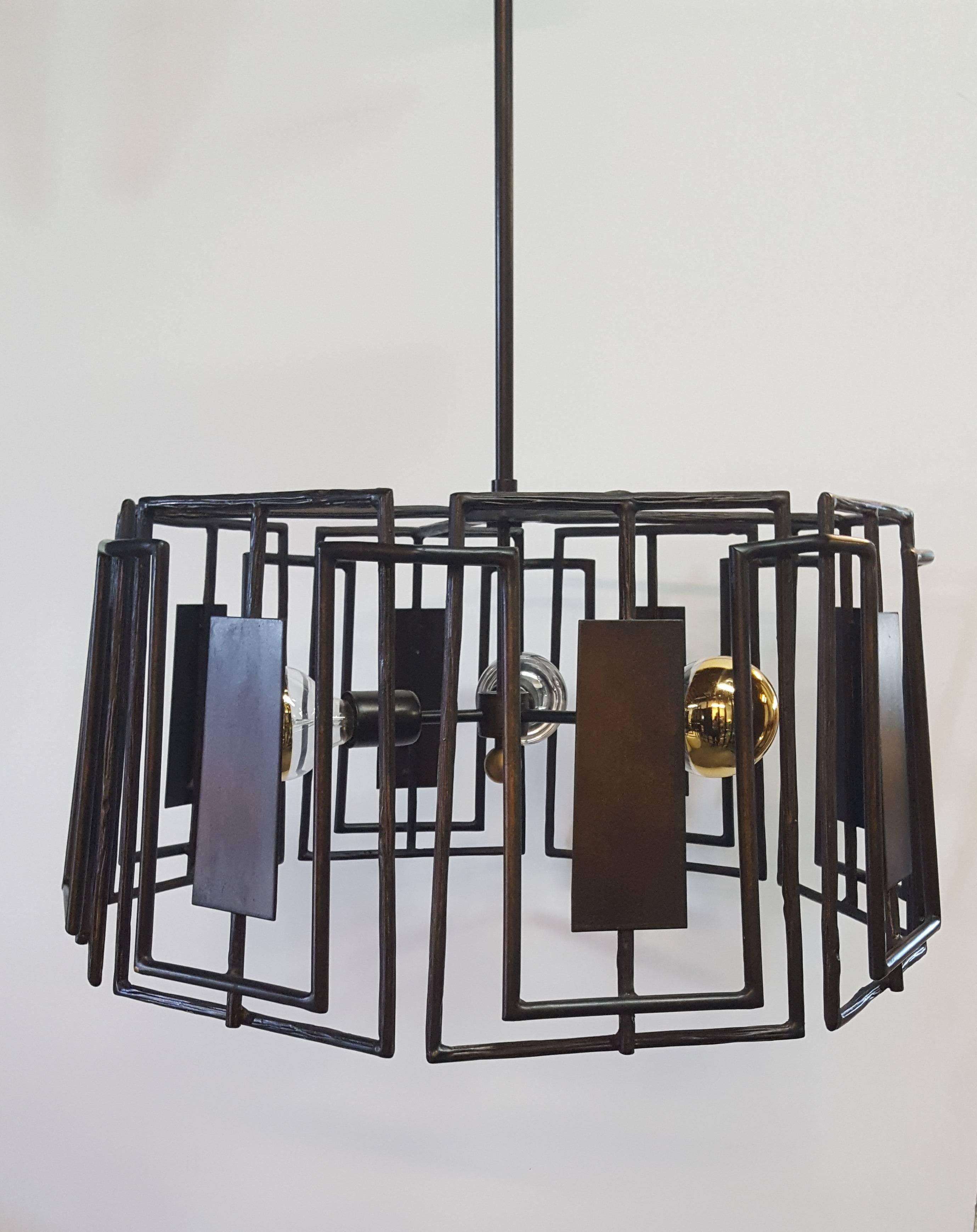 Trellis chandelier by Paul Marra. A modern fixture, in the organic modern or brutalist style. Hand-forged sculptured iron in faux bois pattern that varies throughout. Oil rubbed bronze finish. Brushed brass finial. Lamp bulbs shown as example only,