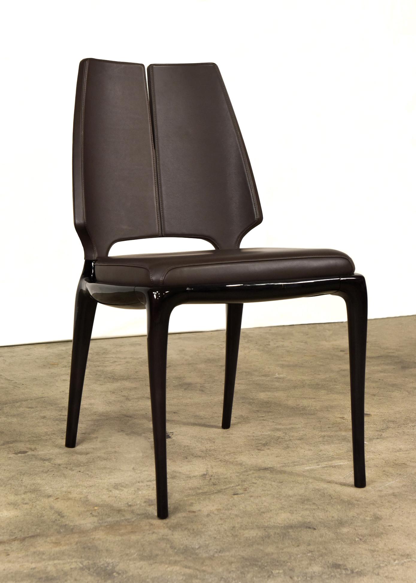 Der schlanke und raffinierte Stuhl Contour mit Armlehnen vereint auf brillante Weise einen nüchternen Geist mit
zeitgenössischer Geschmack. Er ist aus dunkel lackiertem Holz gefertigt und beherbergt den Sitz aus lavafarbenem Leder
kissen, das mit