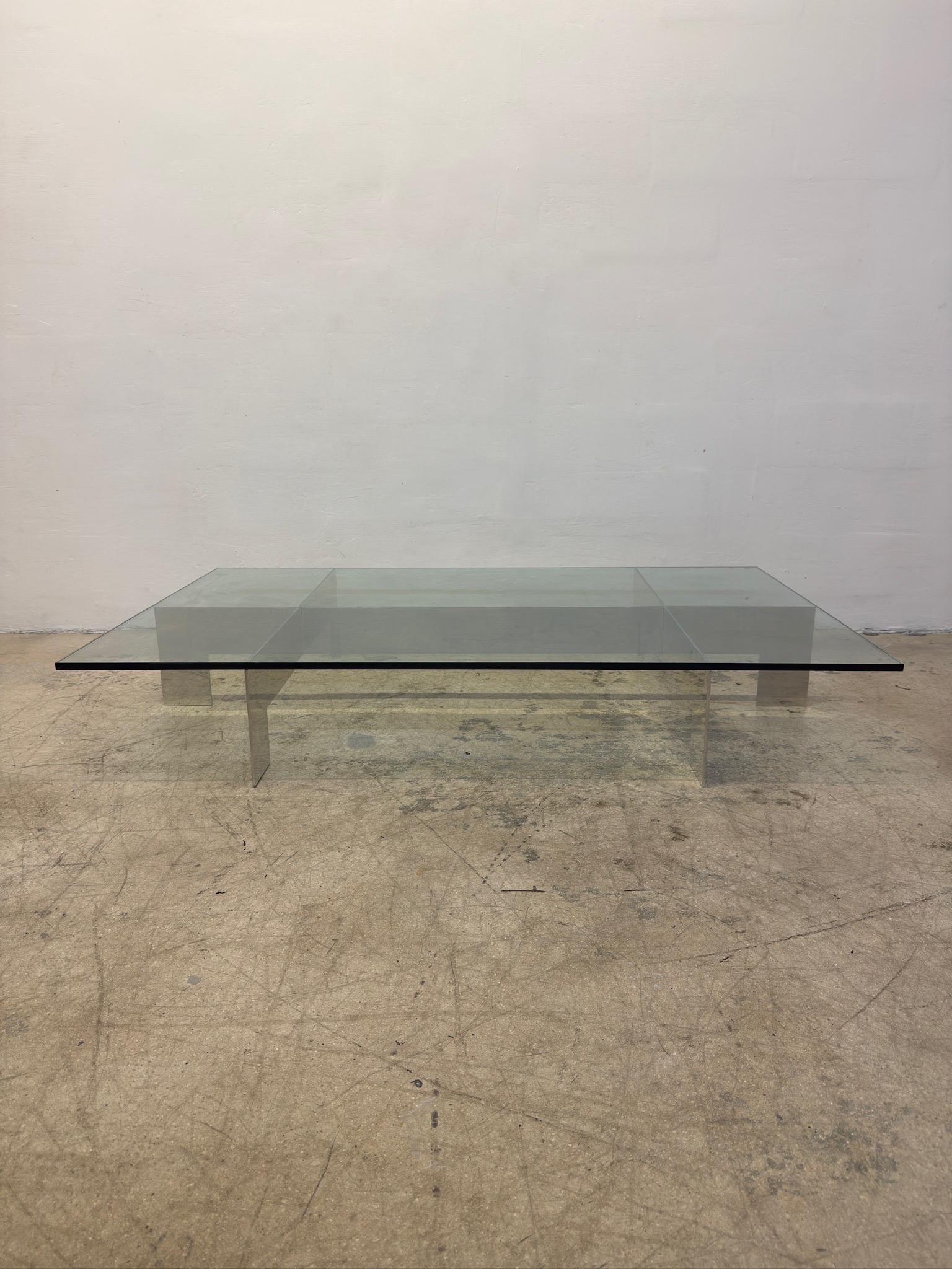 Table à café ou à cocktail de grande taille, à structure basse en aluminium et plateau en verre, conçue par Paul Mayen pour Habitat, dans les années 1970.  

Le plateau en verre à bord poli de 5/8