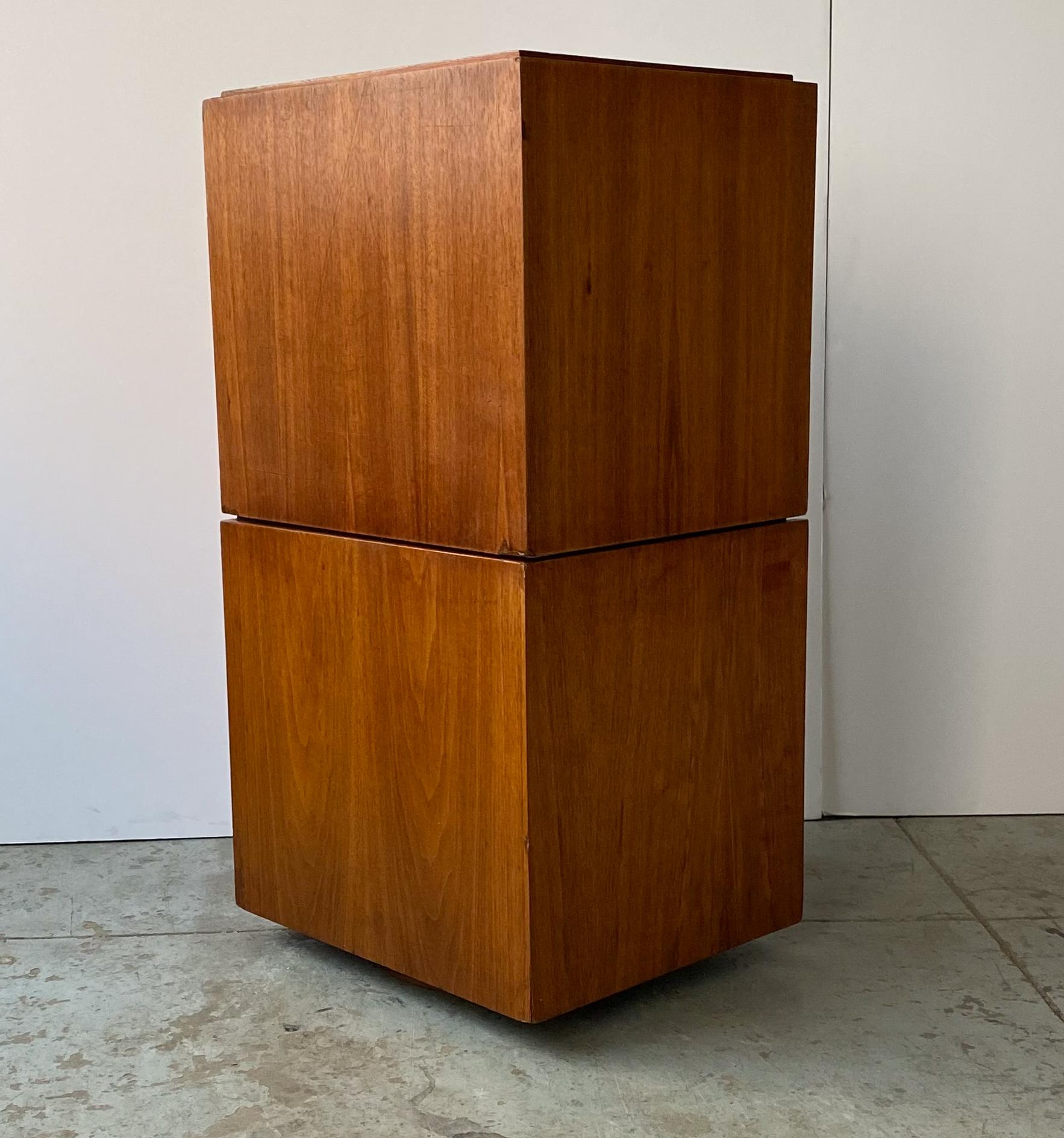 Two-piece stacking and rotating storage cabinet in walnut, each with two open cubbies, designed originally for record storage by Paul Mayen and produced by Habitat/Intrex, circa 1960. The bottom component has a ball-bearing turntable underneath so