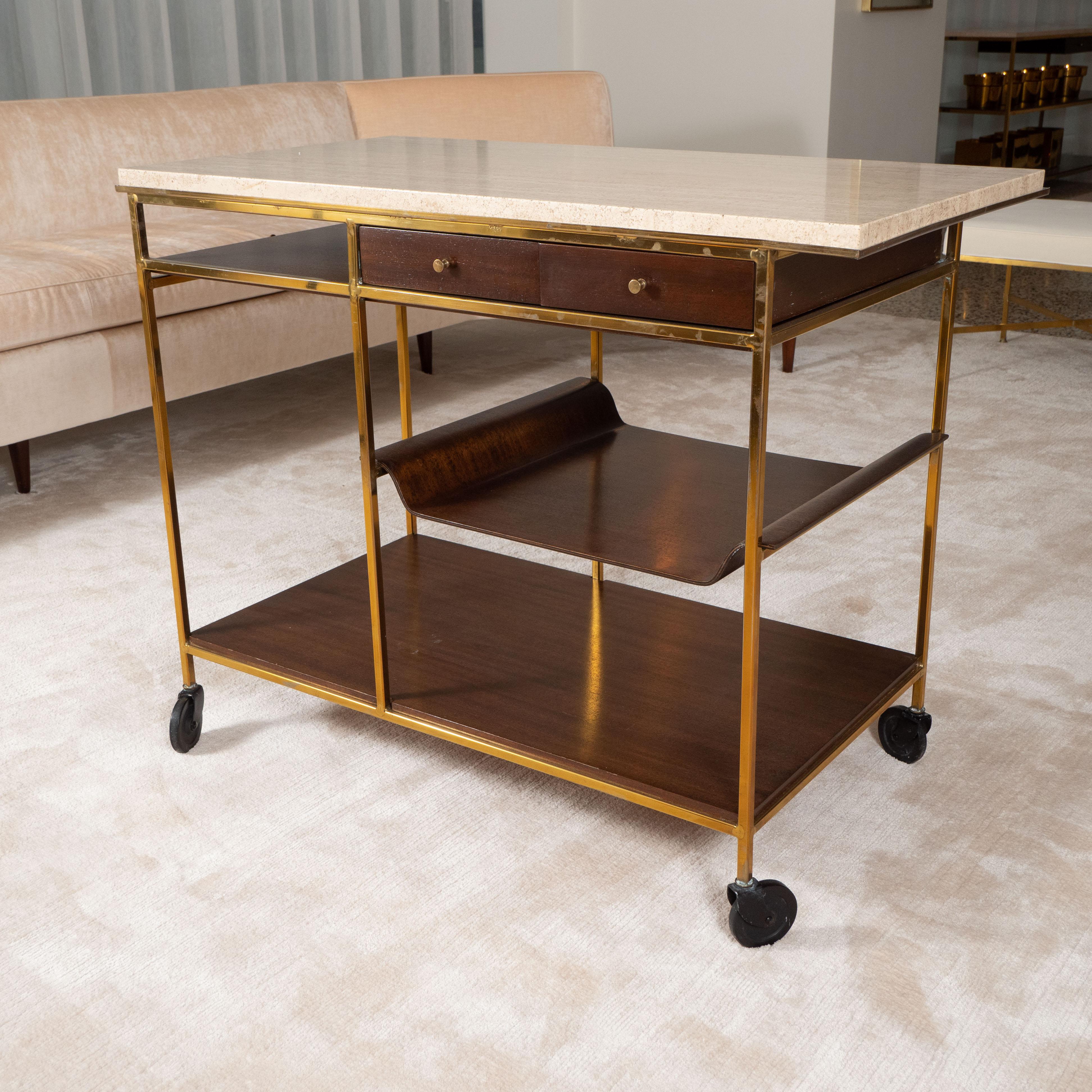 Brass and mahogany bar cart by Paul McCobb; features a travertine top above a slide and detachable tray, complemented by two side by side drawers and multiple shelves.

Signed with label to drawer inscribed calvin grand rapids the irwin collection