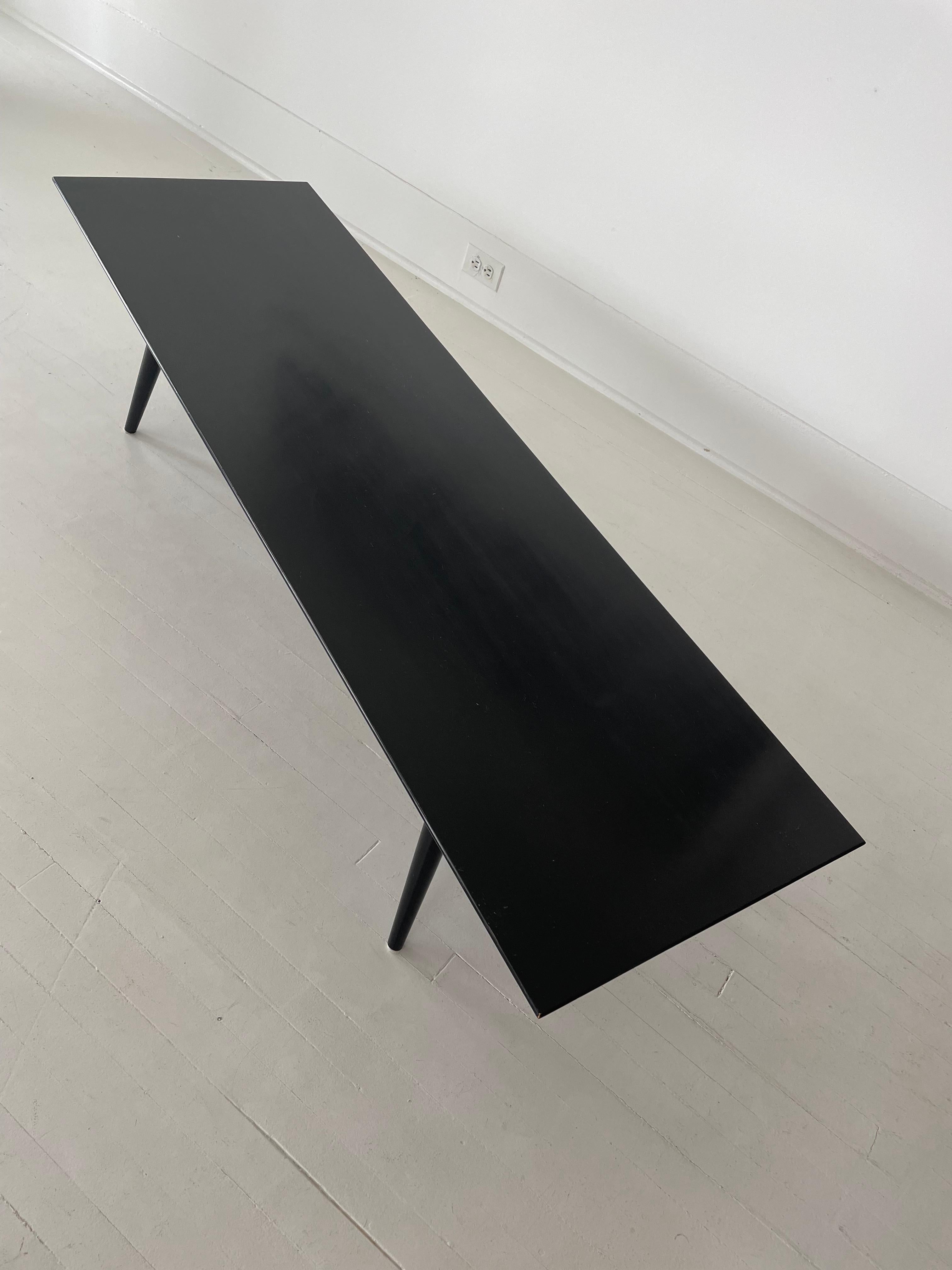 Sleek and minimal, this beautiful black lacquered wood coffee table was part of the Planner Group for Winchendon Furniture Company that was manufactured in the 1950s thru the 1960s. Designed by Paul McCobb. Long and low with dowel splayed legs that