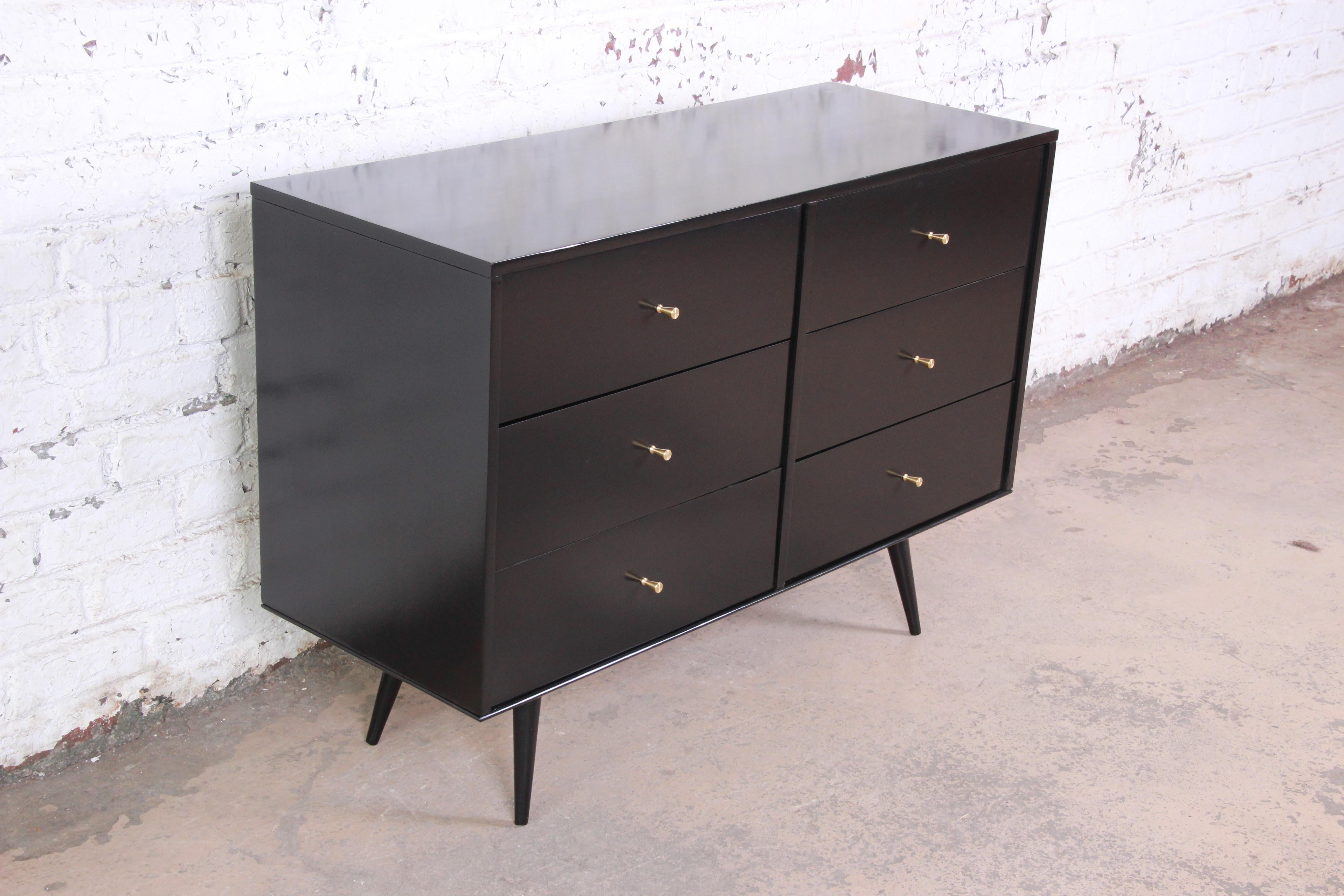 An excellent six-drawer black lacquered Planner Group dresser by Paul McCobb. The dresser sits upon splayed legs and offers six smooth sliding drawers with iconic brass pulls from this McCobb line. The dresser has simply mid-century modern lines as