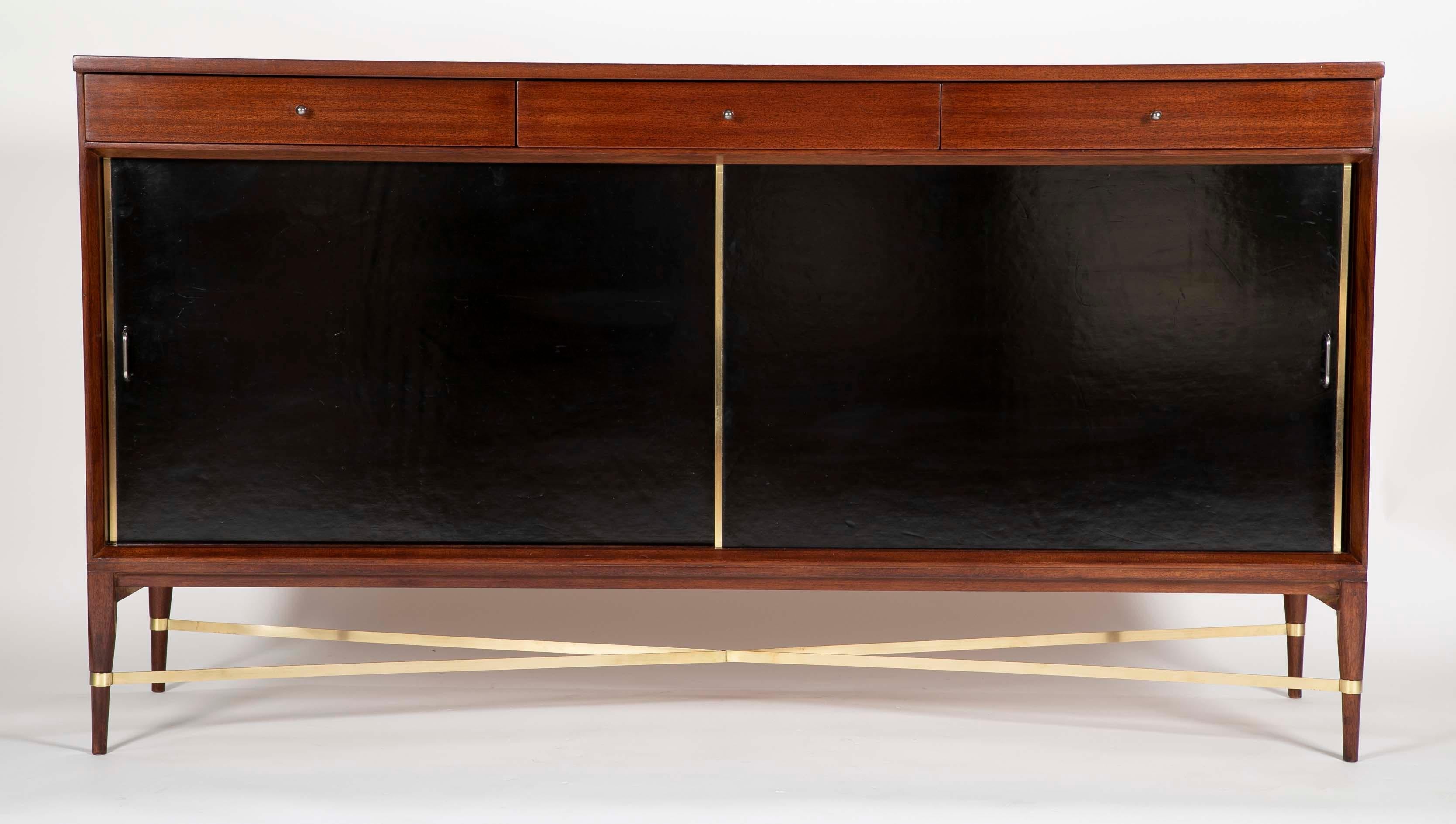 A side board designed by Paul McCobb for Calvin furniture, circa 1965. Having two sliding leather clad doors.