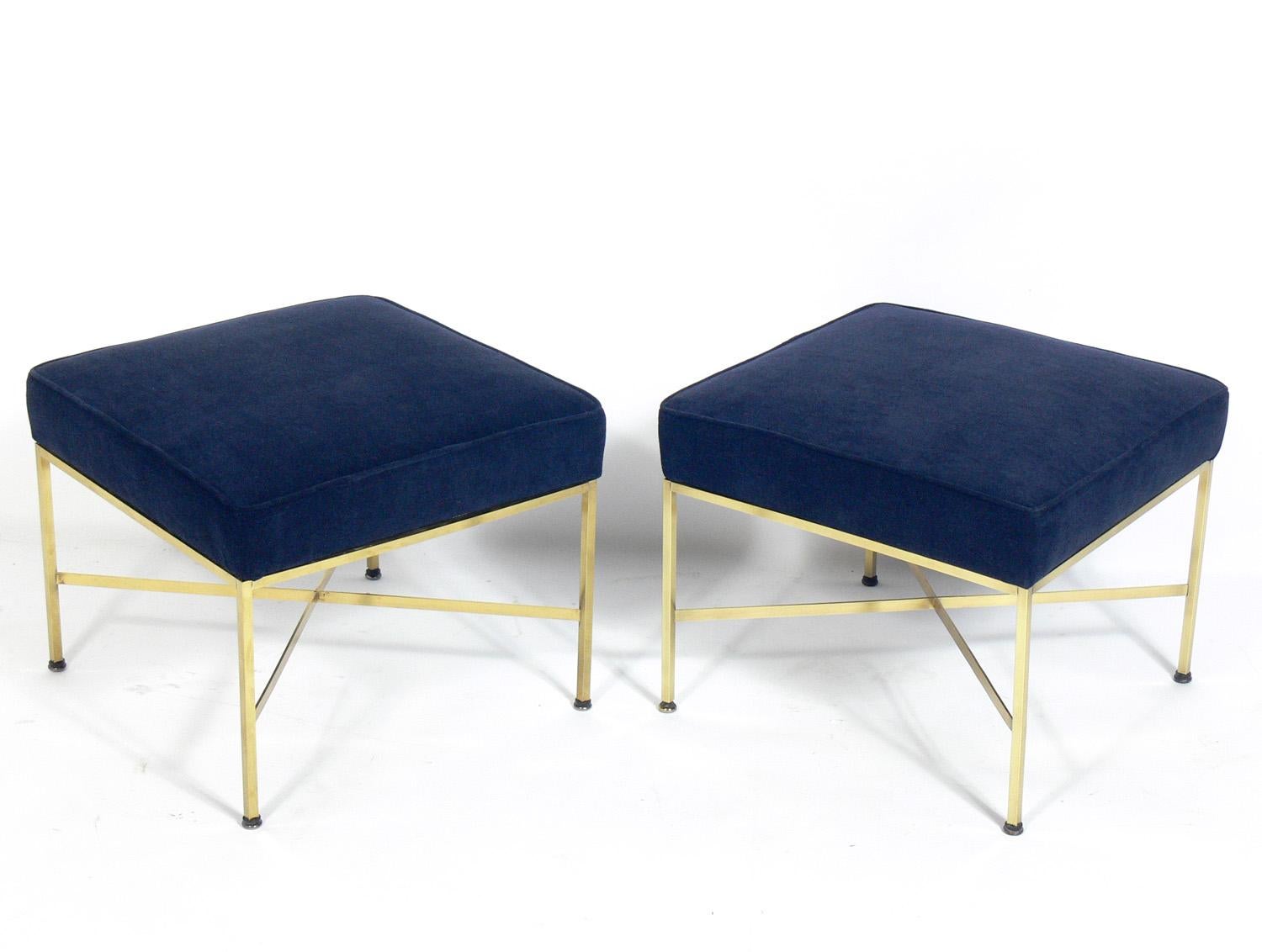 Pair of modern brass X stools, designed by Paul McCobb, American, circa 1950s. They have been polished and lacquered and reupholstered in a navy color velvet.