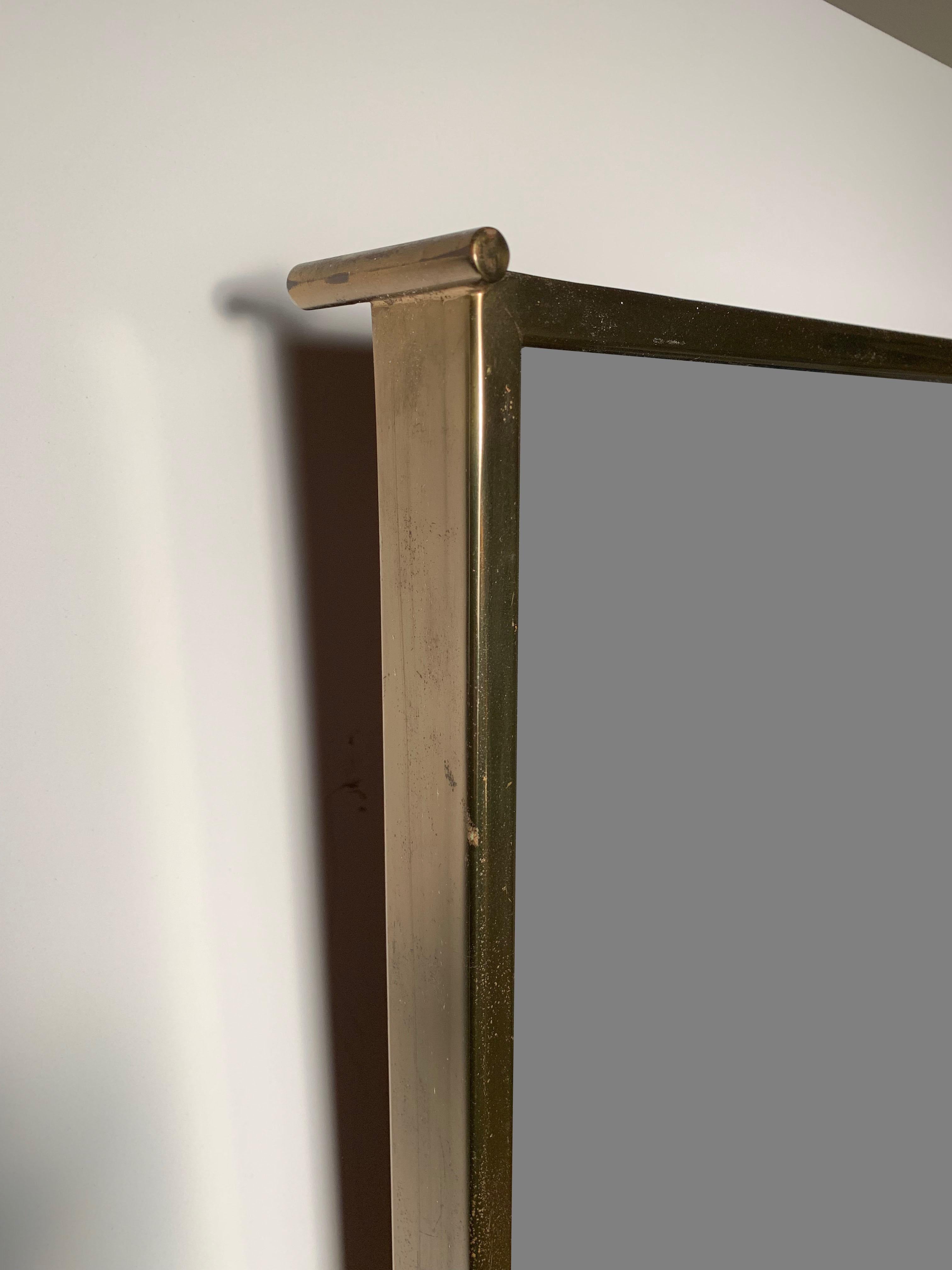 PAUL MCCOBB Brass X Mirror. One of Mccobb's strongest Mirror Designs. Brass Pegs at each corner to suspend the mirror off the wall. Large brass X form on front of mirror. Decorative yet not detracting from the function the mirror serves.