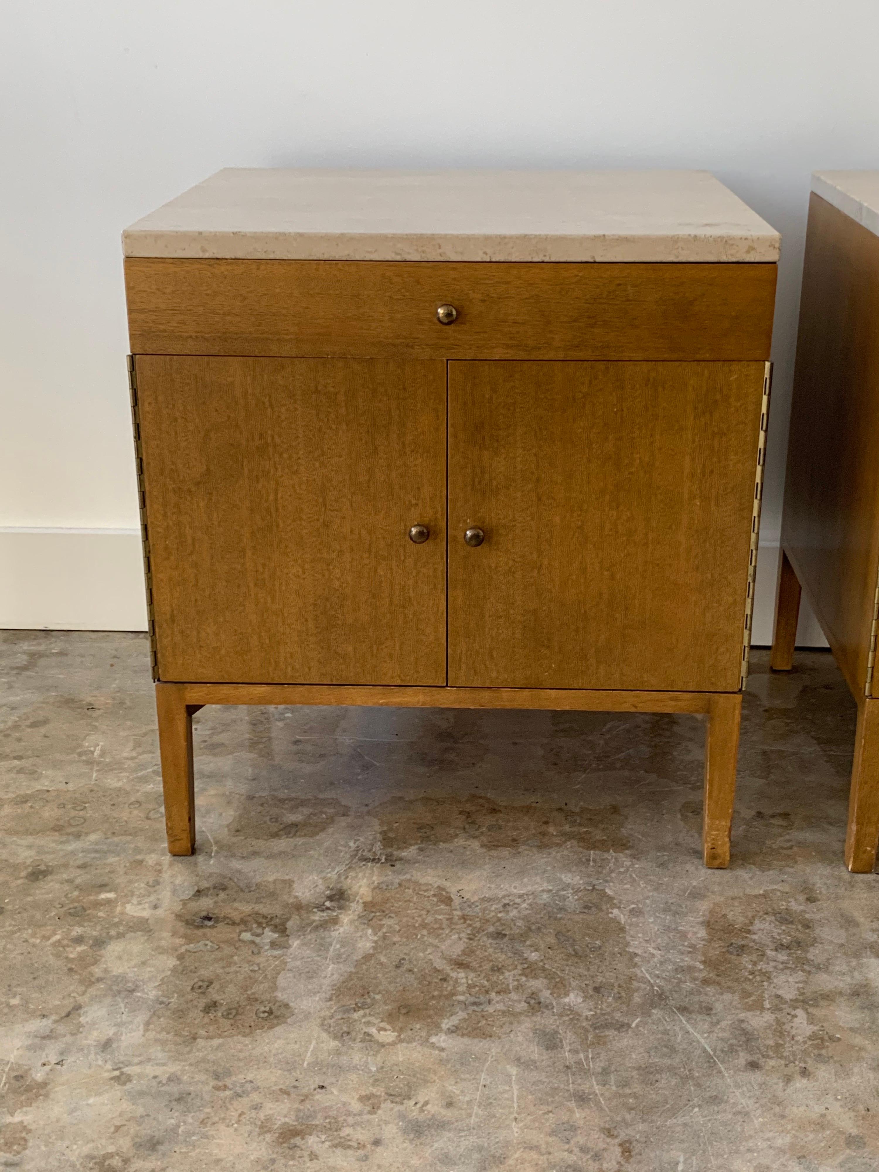 Mid-Century Modern pair of night tables designed by Paul McCobb, from the Irwin Collection for Calvin Furniture of Grand Rapids, circa 1960. Solid walnut with Italian travertine tops. Solid brass hinges and knobs.
Tables have a top drawer above a