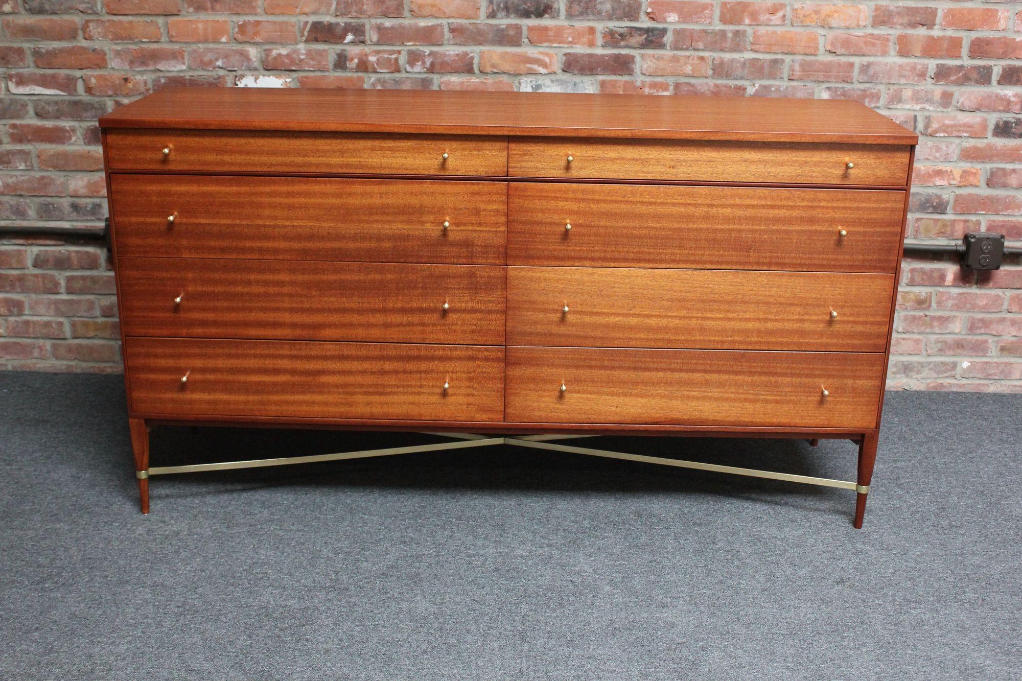 Paul Mccobb Calvin Group eight-drawer double dresser / lowboy cabinet manufactured by Directional Furniture (ca. early 1950s, USA).
Composed of a stained mahogany chest with brass tear-drop pulls supported by carved, tapered legs and brass 'x'
