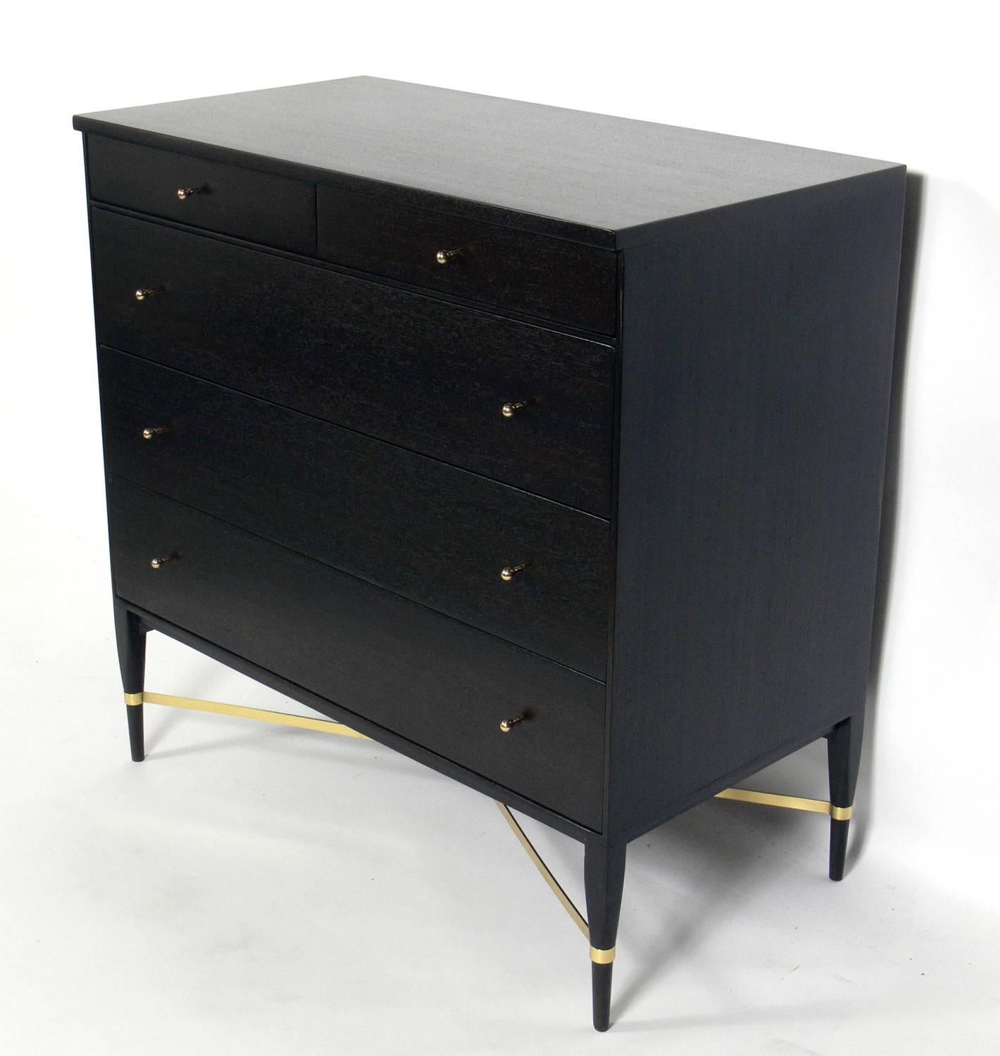 Mid-Century Modern dresser or chest of drawers, designed by Paul McCobb for Calvin, American, circa 1950s. It has been completely restored in an ultra deep brown color with the brass hardware polished and lacquered. We have a pair of these