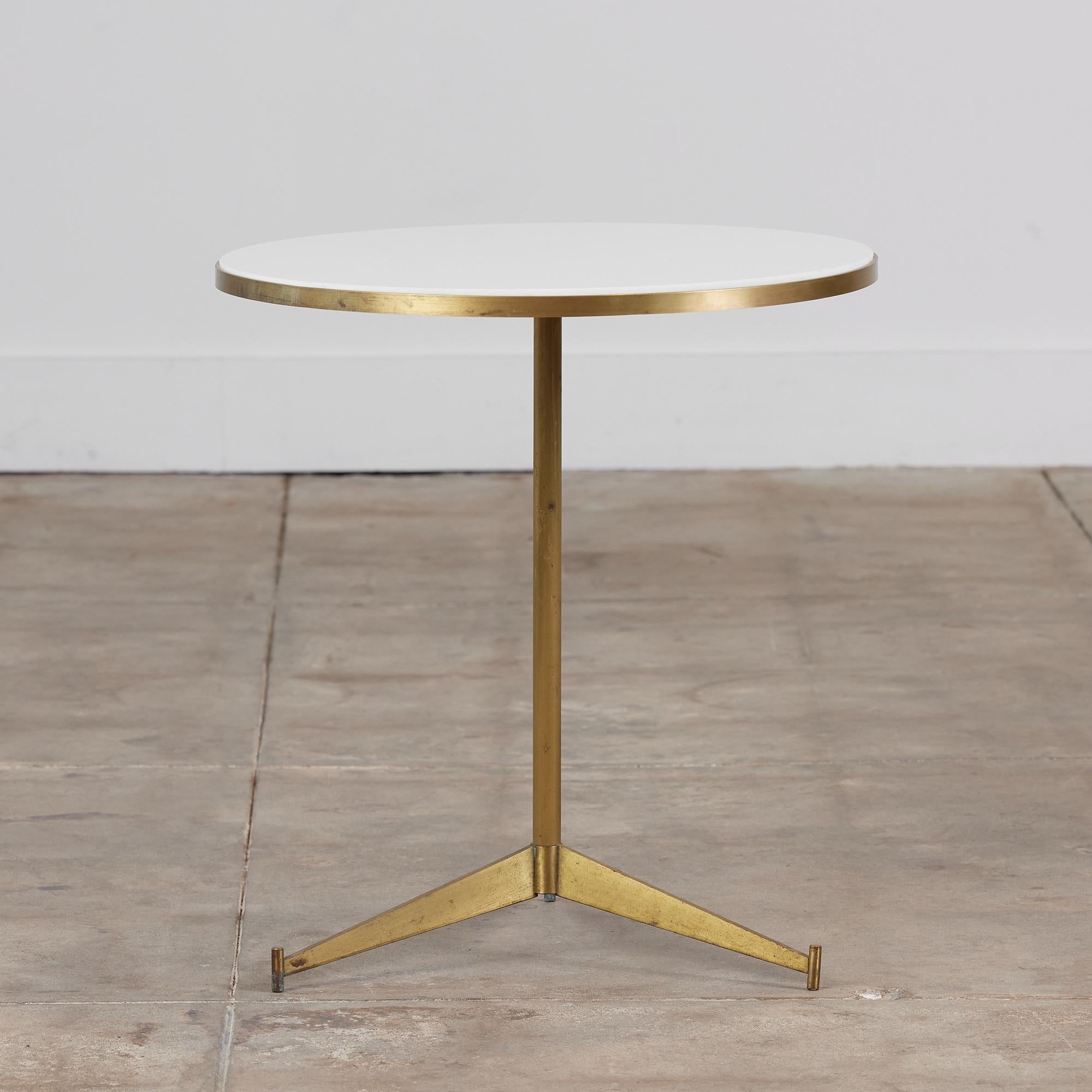 Paul McCobb brass and white vitrolite glass cigarette table for Directional, c. 1950s, USA. This table was only produced for a short period of time which makes it a rarer find. A round white vitrolite glass top rests inside the delicate brass frame.