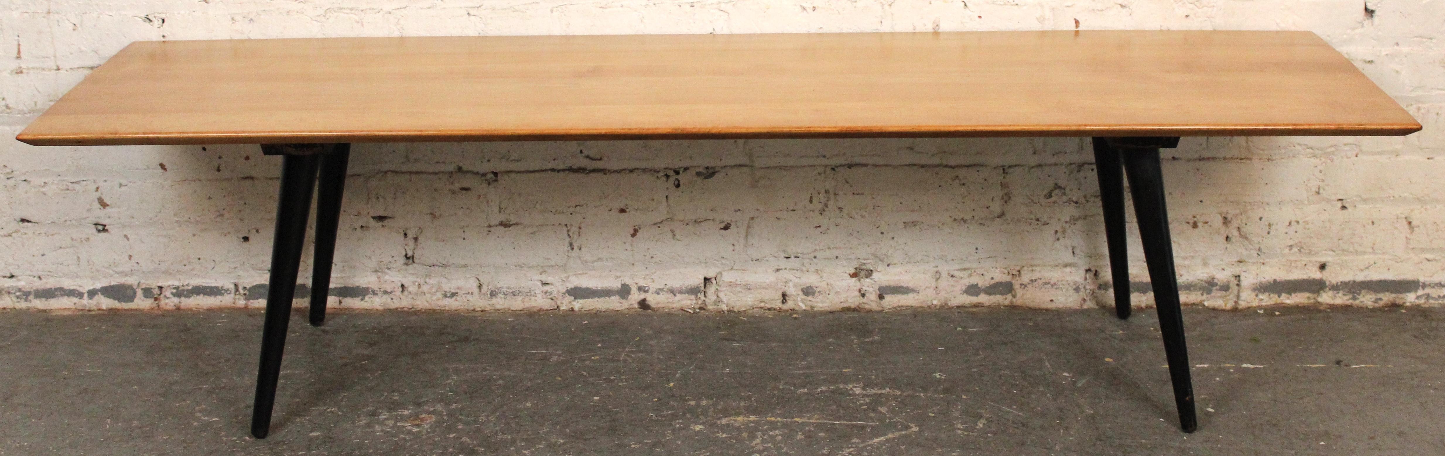 Classic and clean-lined, this vintage two-tone coffee table was designed by Paul McCobb for his iconic Planner Group series by Winchendon Furniture. Crafted from solid maple with McCobb’s signature tapered legs in an ebonized finish and minimalist
