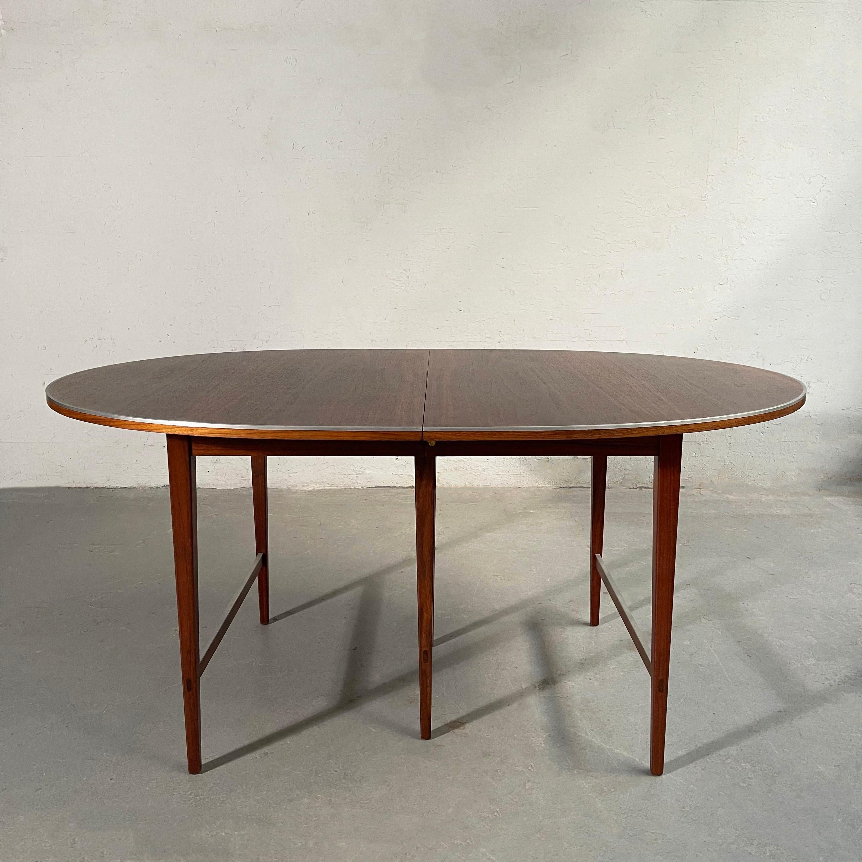 Elegant, Mid-Century Modern, oval, mahogany, extension dining table by Paul McCobb for H. Sacks & Sons, Connoisseur Collection features a subtle chrome trim on it's top and leg brackets. The table has four 16 inch leaves that extend the table from