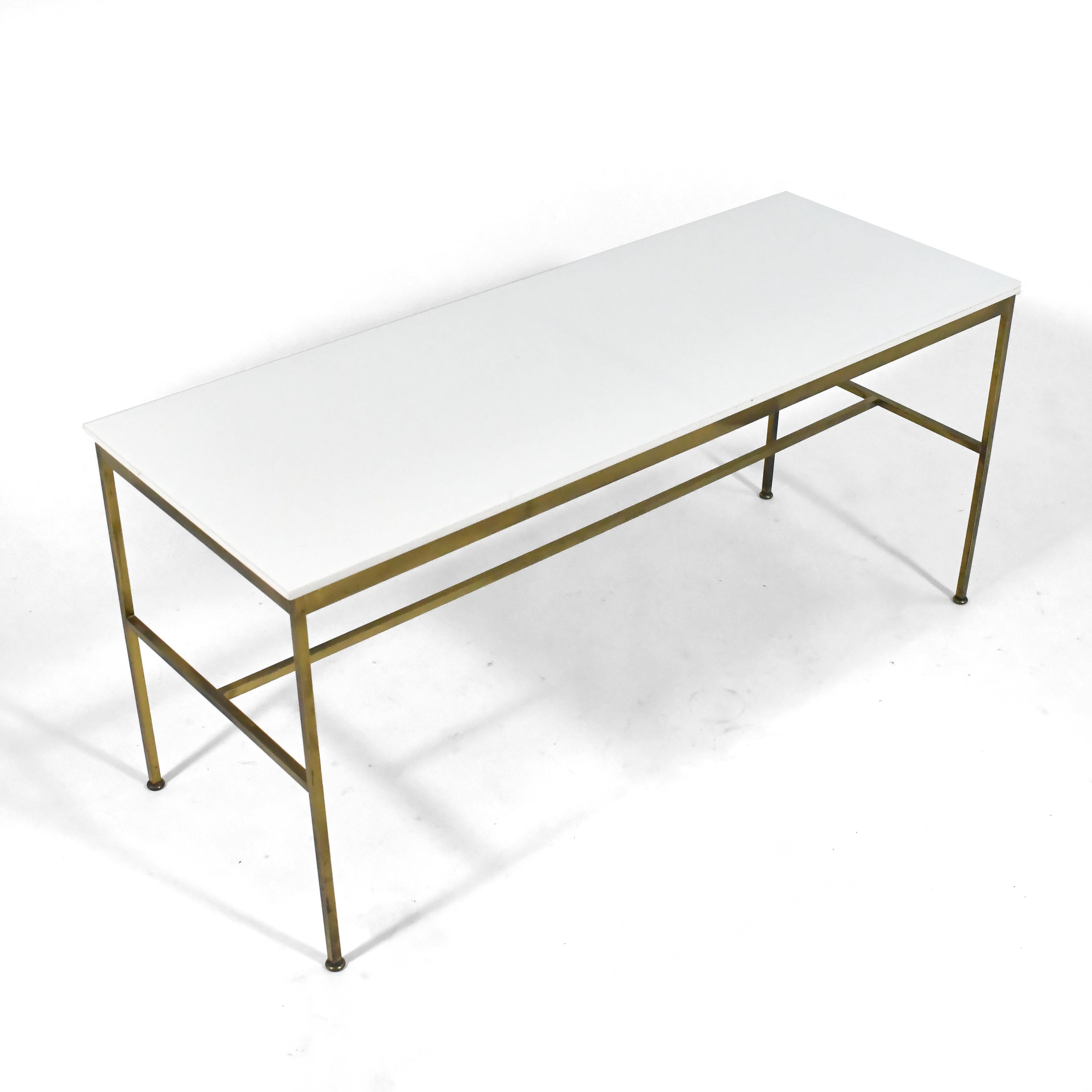 A stunning example of McCobb's masterful, minimalist design aesthetic, this sublime console table features a brass base which supports a top of opaque white Vitrolite glass.

This rare vintage table is in very good original condition with a most