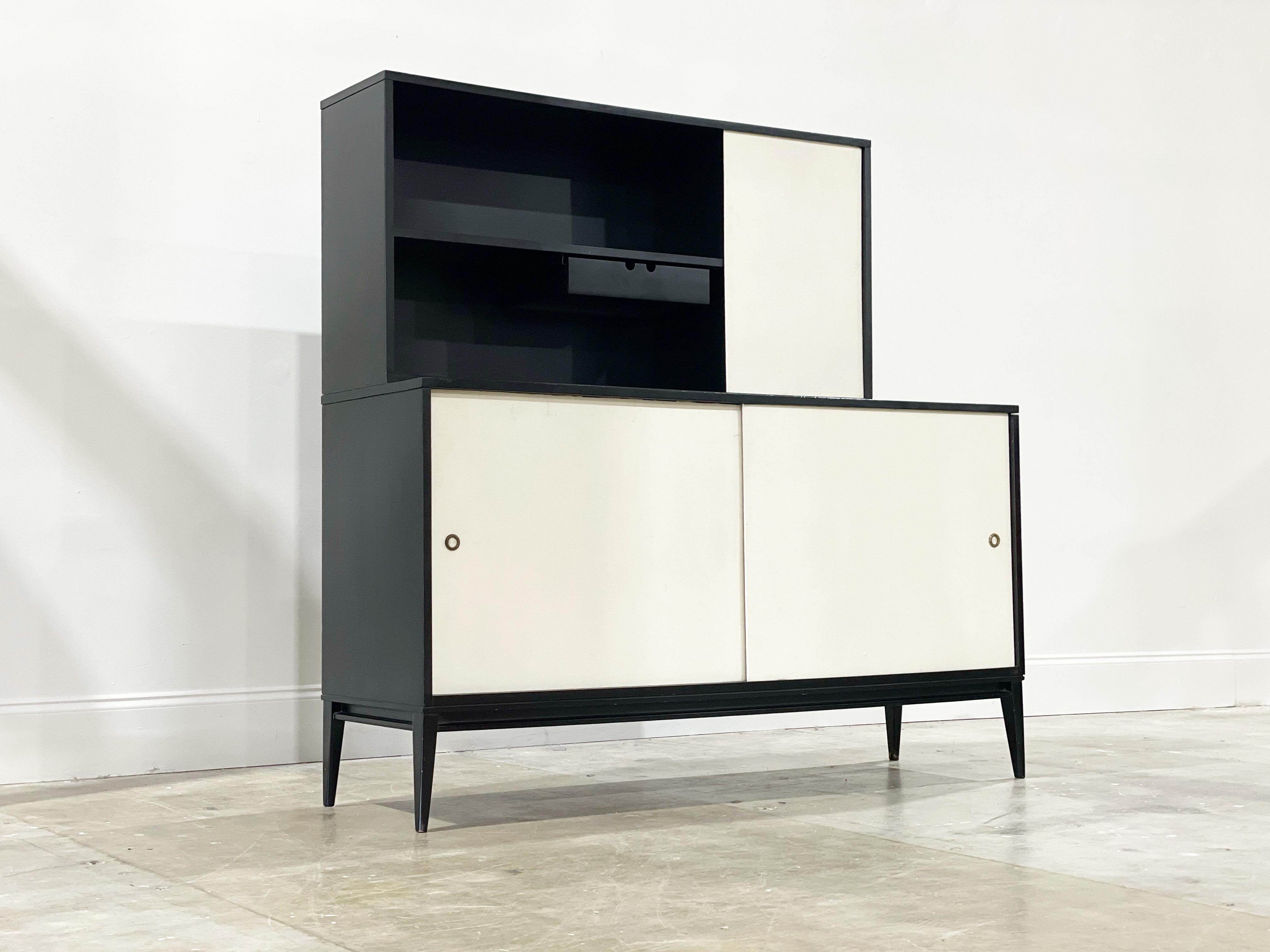 Early Planner Group sliding door credenza and hutch top by Paul McCobb for Winchedon. All original black lacquer. White grass cloth sliding doors. Upper cabinet includes rare integrated drawer below the left side shelf. Upper cabinet can be placed