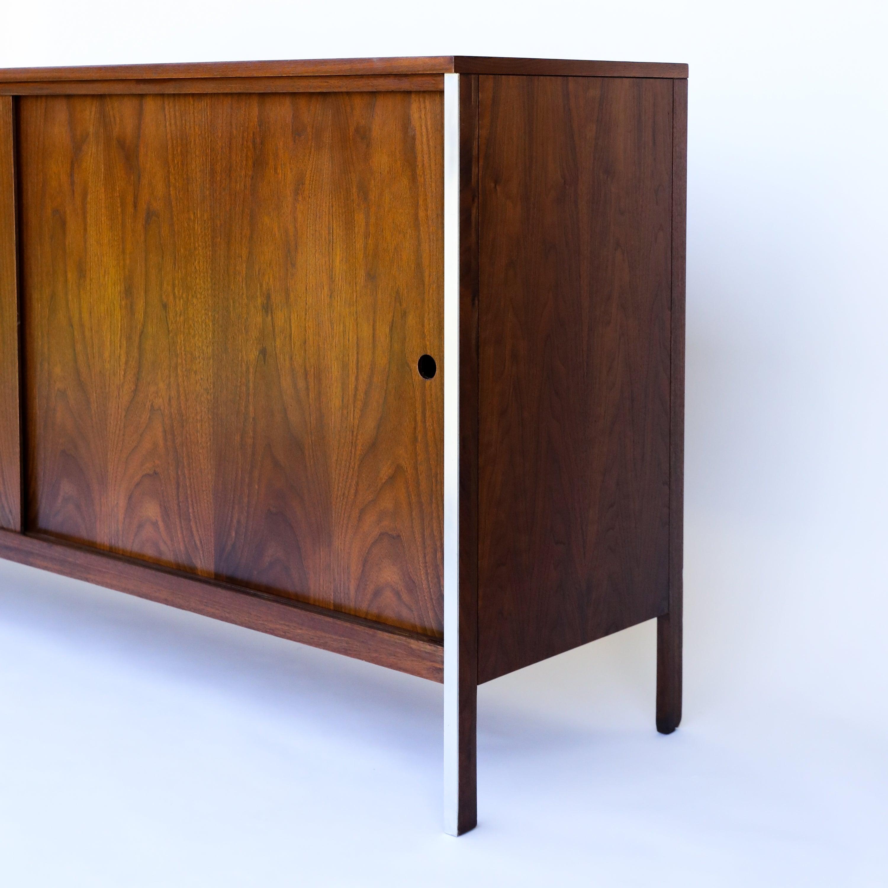 

This is a classic two-door cabinet designed by Paul McCobb for Calvin Furniture, circa the early 1960s. This piece is executed in exquisite walnut with two drawers on the left side and one adjustable shelf on the right side covered by two sliding