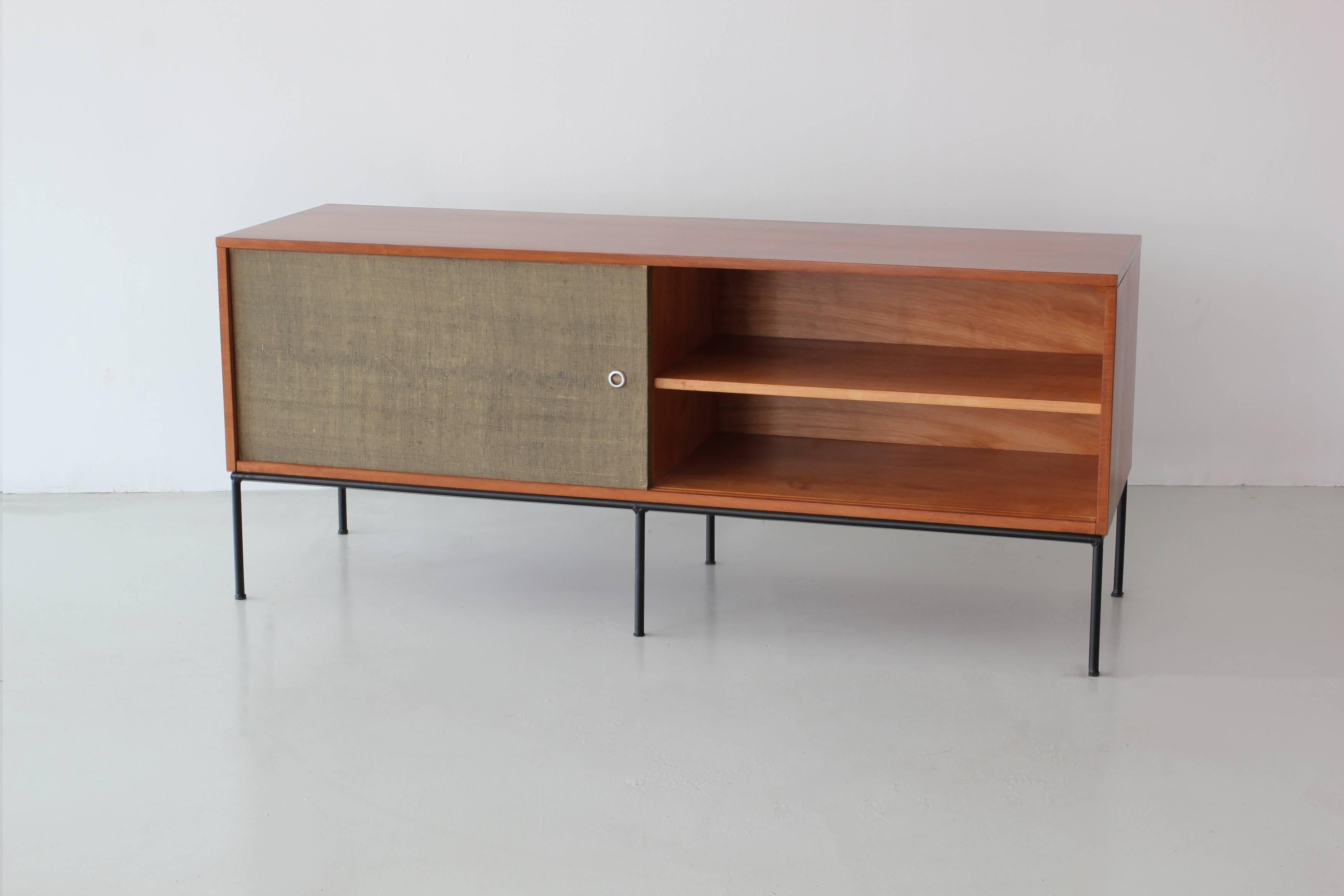 Paul McCobb credenza with sliding caned doors and open shelving on black iron base. 

Wood has been refinished/restored and caning is original with imperfections as photographed.