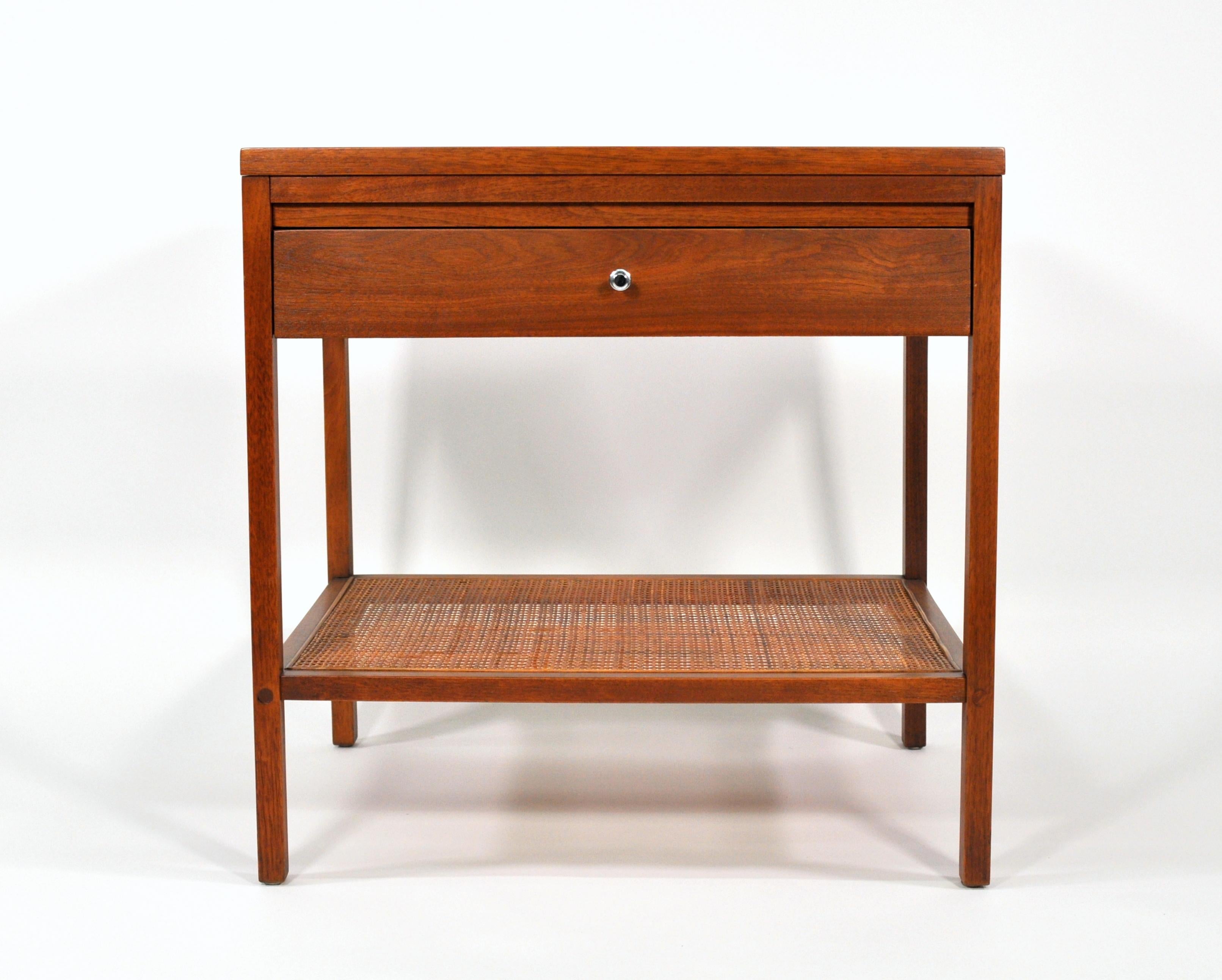 A rare Mid-Century Modern end or bedside table designed by Paul McCobb for the Lane Delineator series, which was only produced between 1961 and 1965. The walnut nightstand features a rosewood top, a single drawer with signature pull and a caned