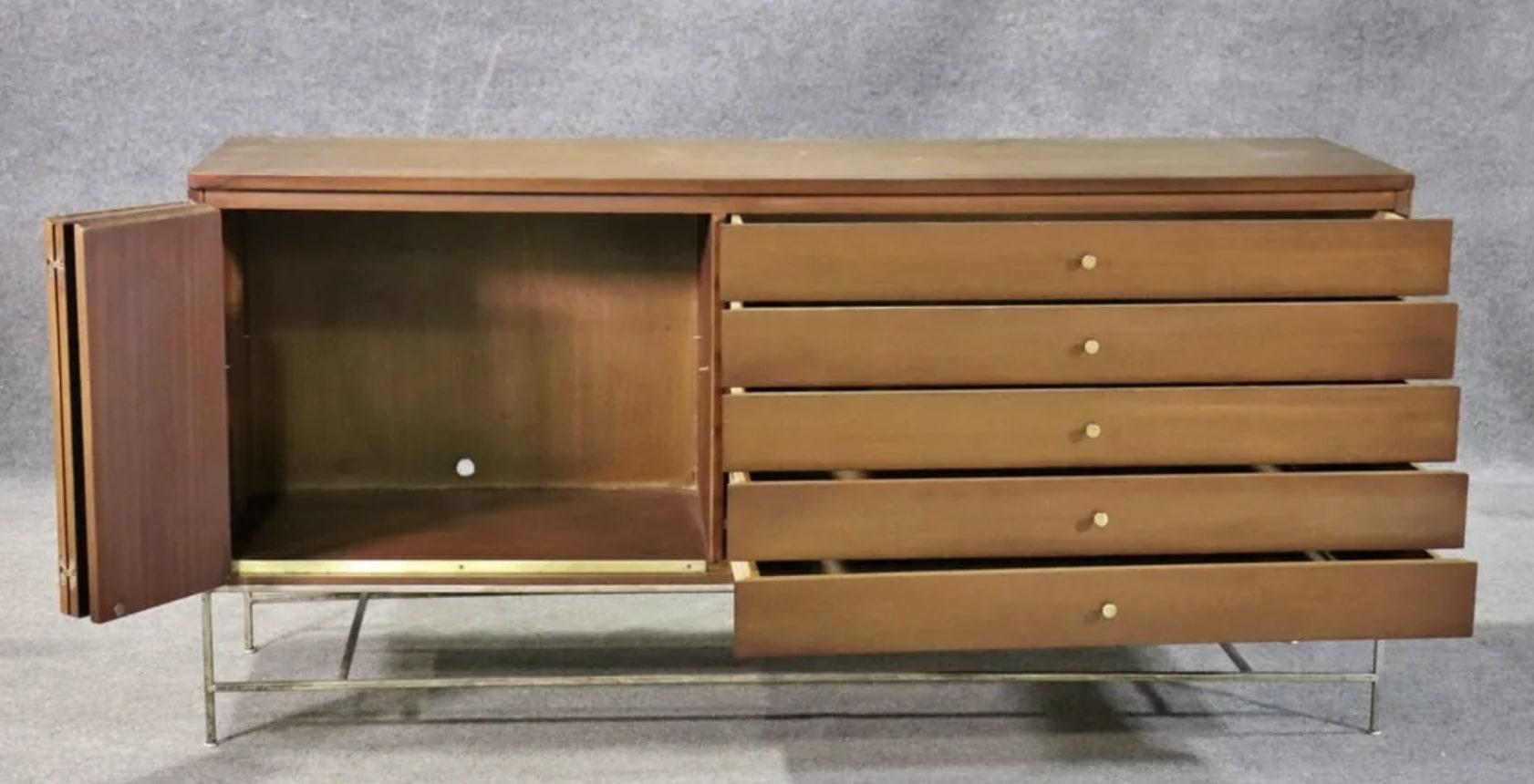 Long multi-use unit designed by Paul McCobb for his Irwin Collection. Made of mahogany wood grain and accenting brass hardware. Left side has a bi-fold door and cabinet storage, the right has five wide drawers.
Please confirm location NY or NJ
