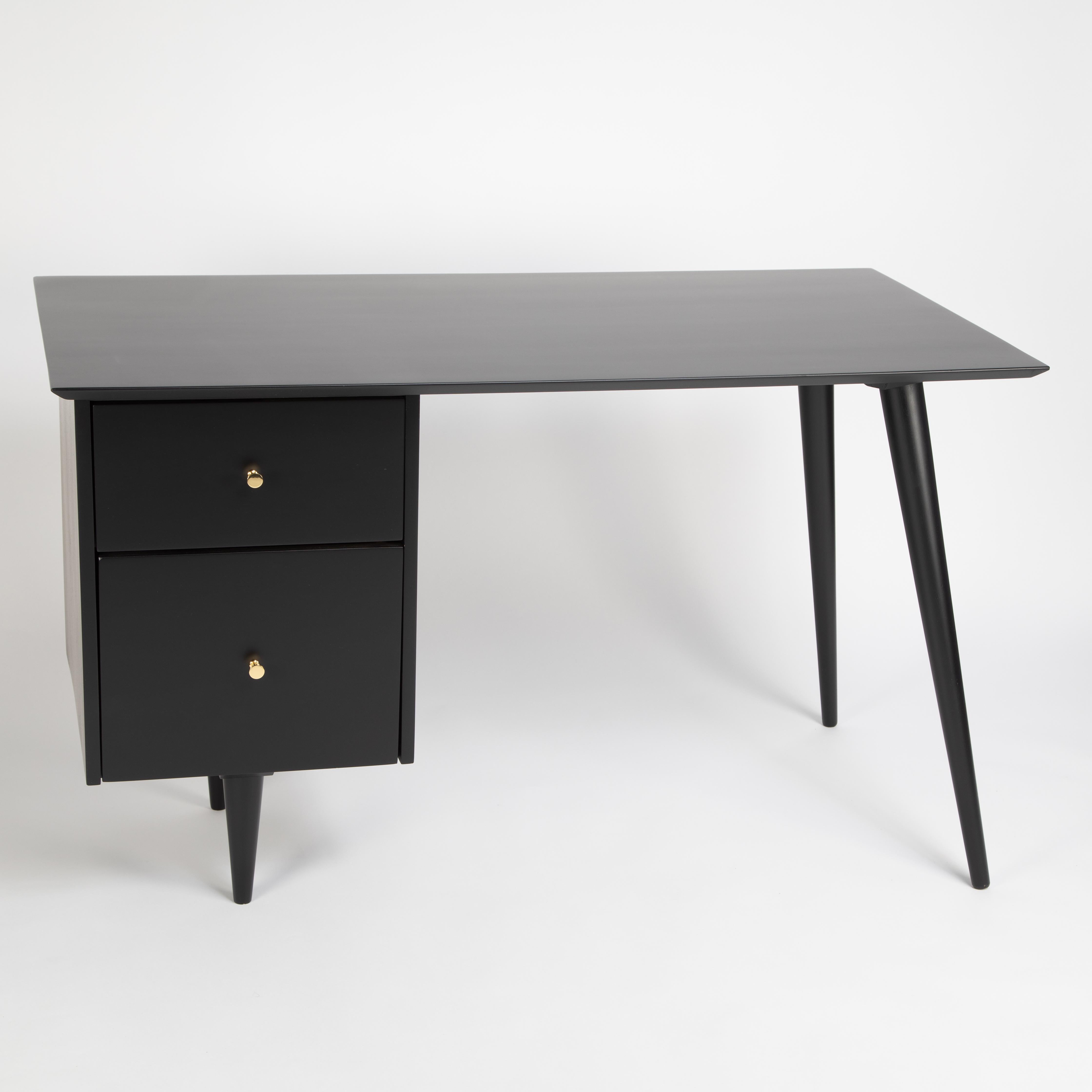 Elegant desk by American design icon Paul McCobb, produced for his Planner Group collection for Winchendon Furniture, circa 1950s. This piece is constructed of solid maple and features McCobb's signature tapered splayed legs and conical pulls in