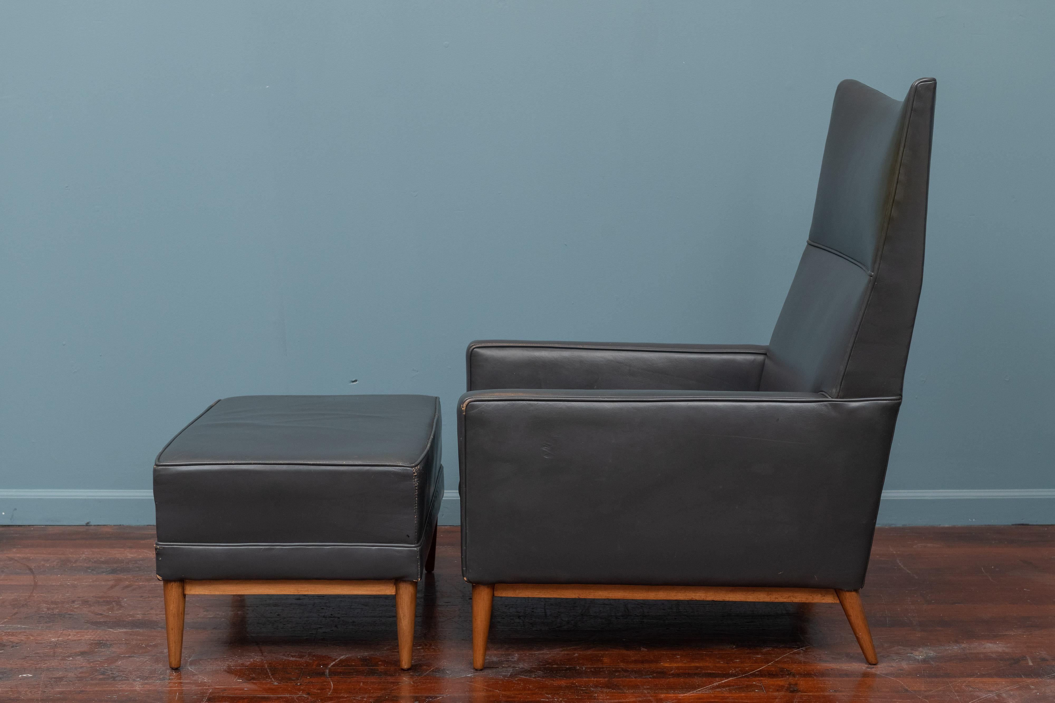 Paul McCobb design high back lounge chair and ottoman, model 314 for Custom Craft. In the original charcoal grey leather on a newly refinished stained birch base in very good usable condition with patina.