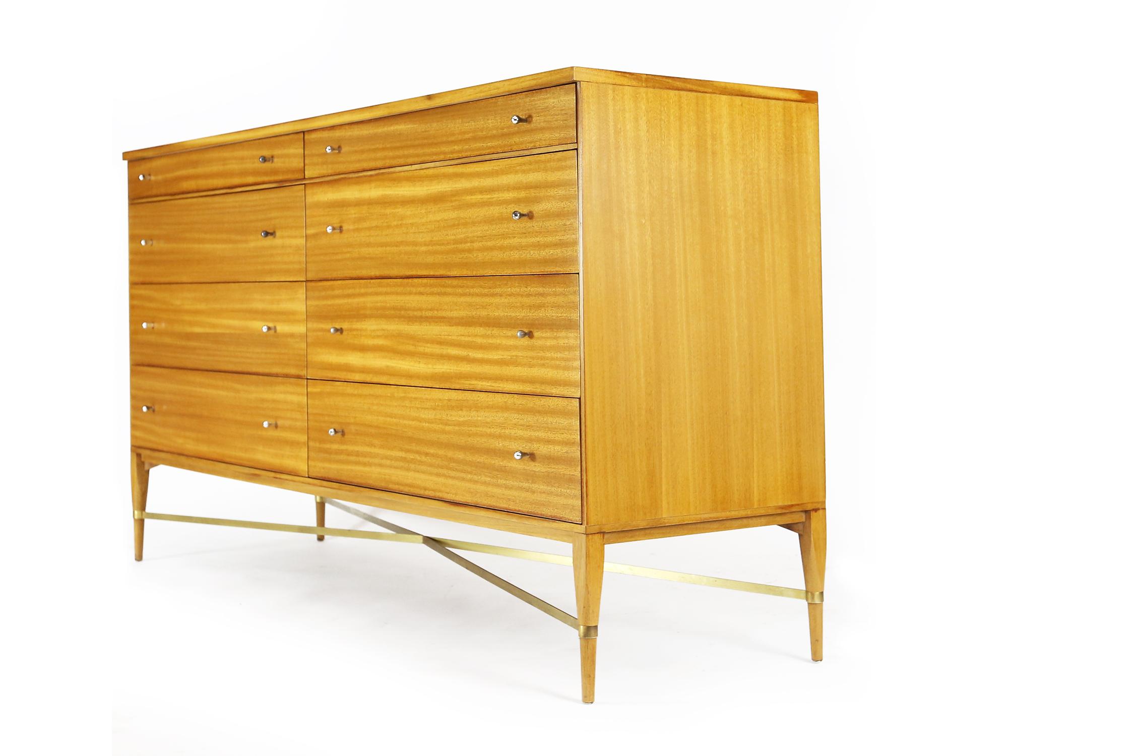 Paul McCobb for Calvin eight-drawer dresser with brass cross stretchers. Bleached ribbon mahogany. Expertly refinished and restored to it's original finish. With the original Calvin label in one of the drawers.