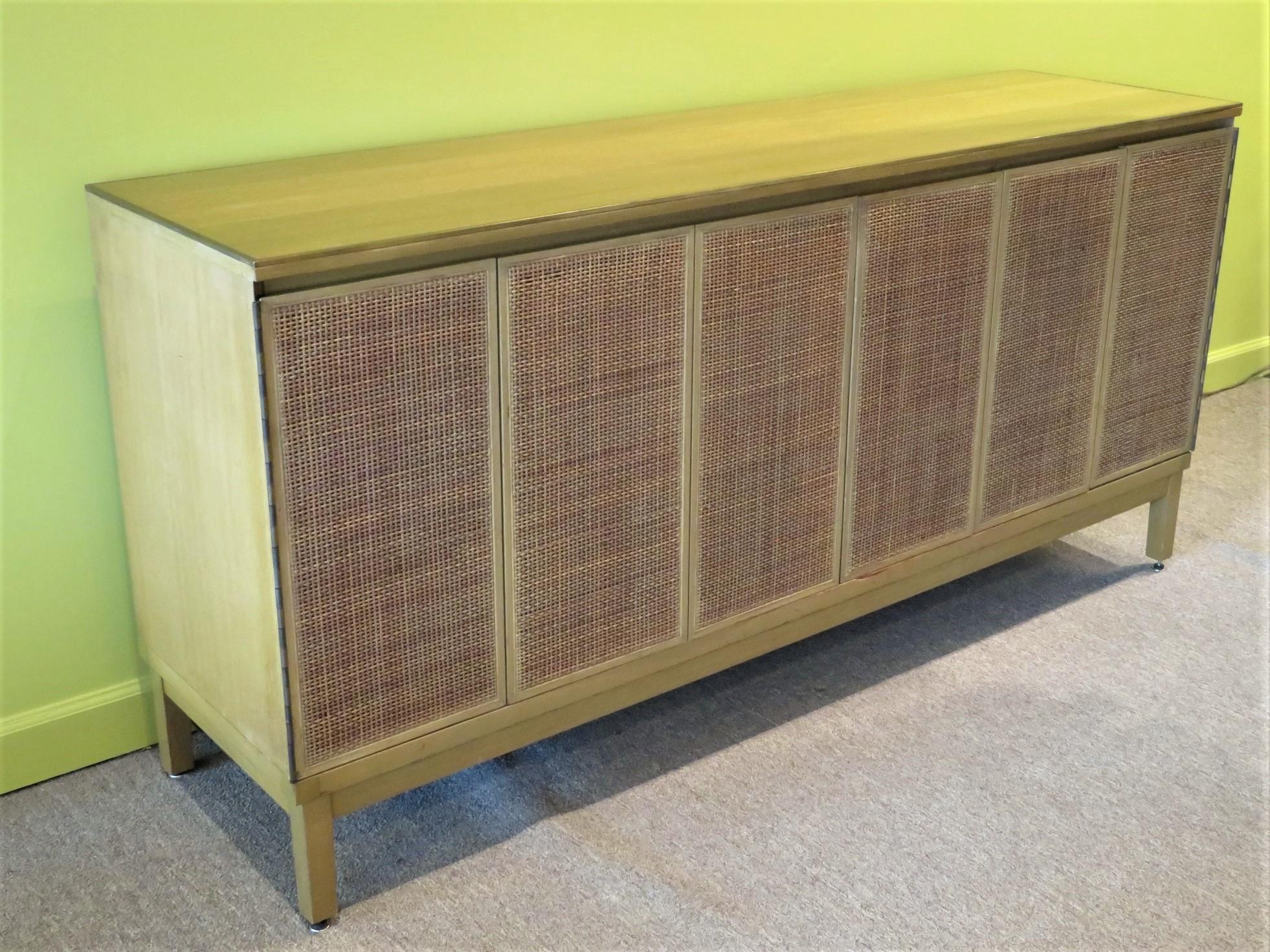 Mid-Century Modern 1950's bleached mahogany Dresser by Paul McCobb for Calvin Furniture with cane front tri-fold doors. The dresser sports a brass band around its top's edge and 8 leather lined drawers. The bleached mahogany has a golden