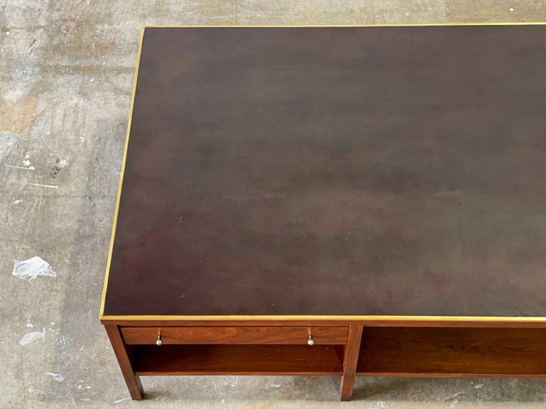 Paul McCobb for Calvin midcentury modern coffee table in walnut, leather and brass. Oversized rectangular cocktail table with one drawer and lower shelves for storage. Modern, minimalist and refined design. Perfect juxtaposition of materials.
