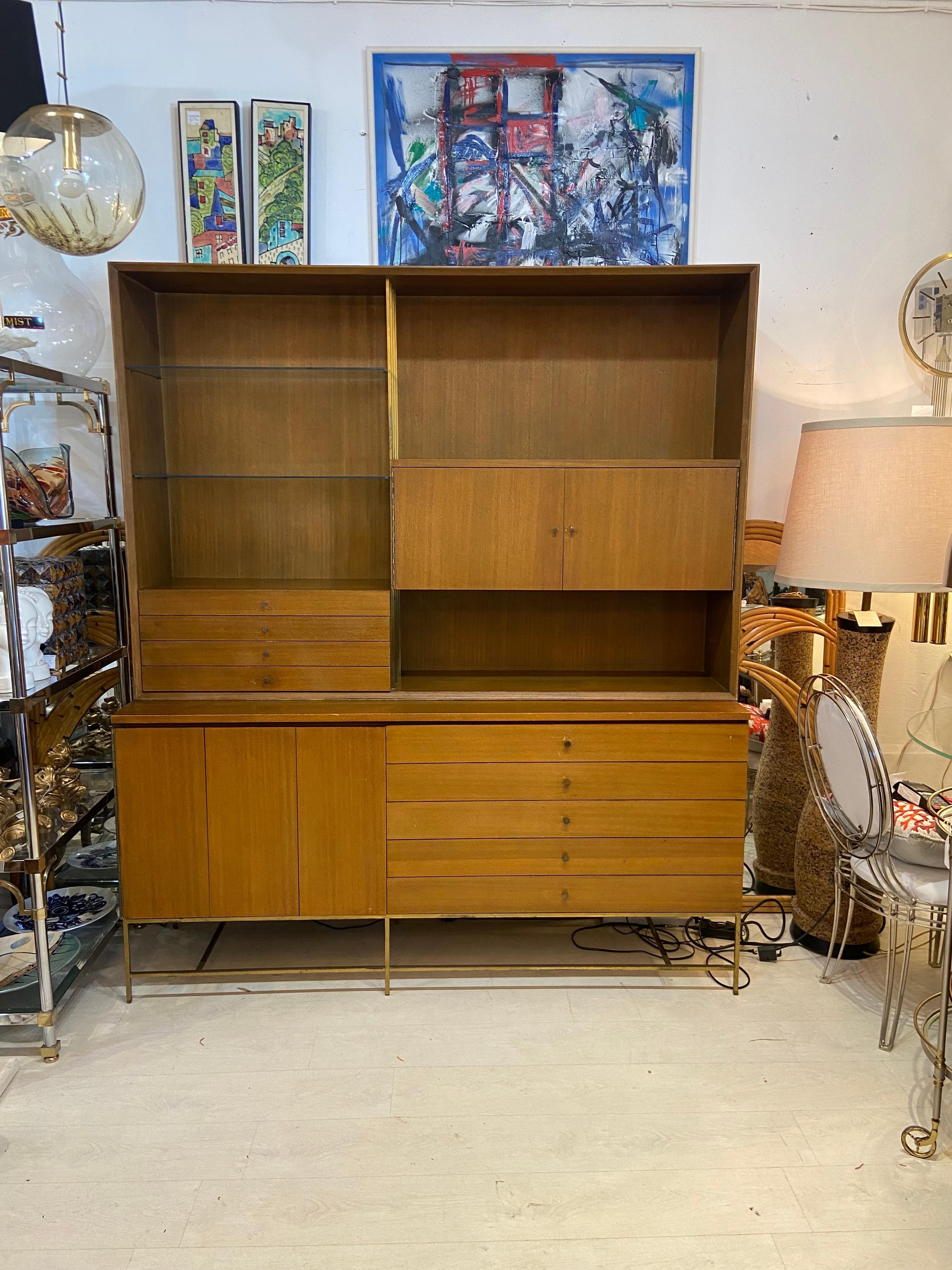 Paul Mccobb for Calvin circa 1950s. Two-part cabinet. The upper unit have a glass shelves doors and four drawers. The lower unit with five drawers and doors. Solid walnut with brass hardware and square brass tubing supporting frame and legs 84 “high