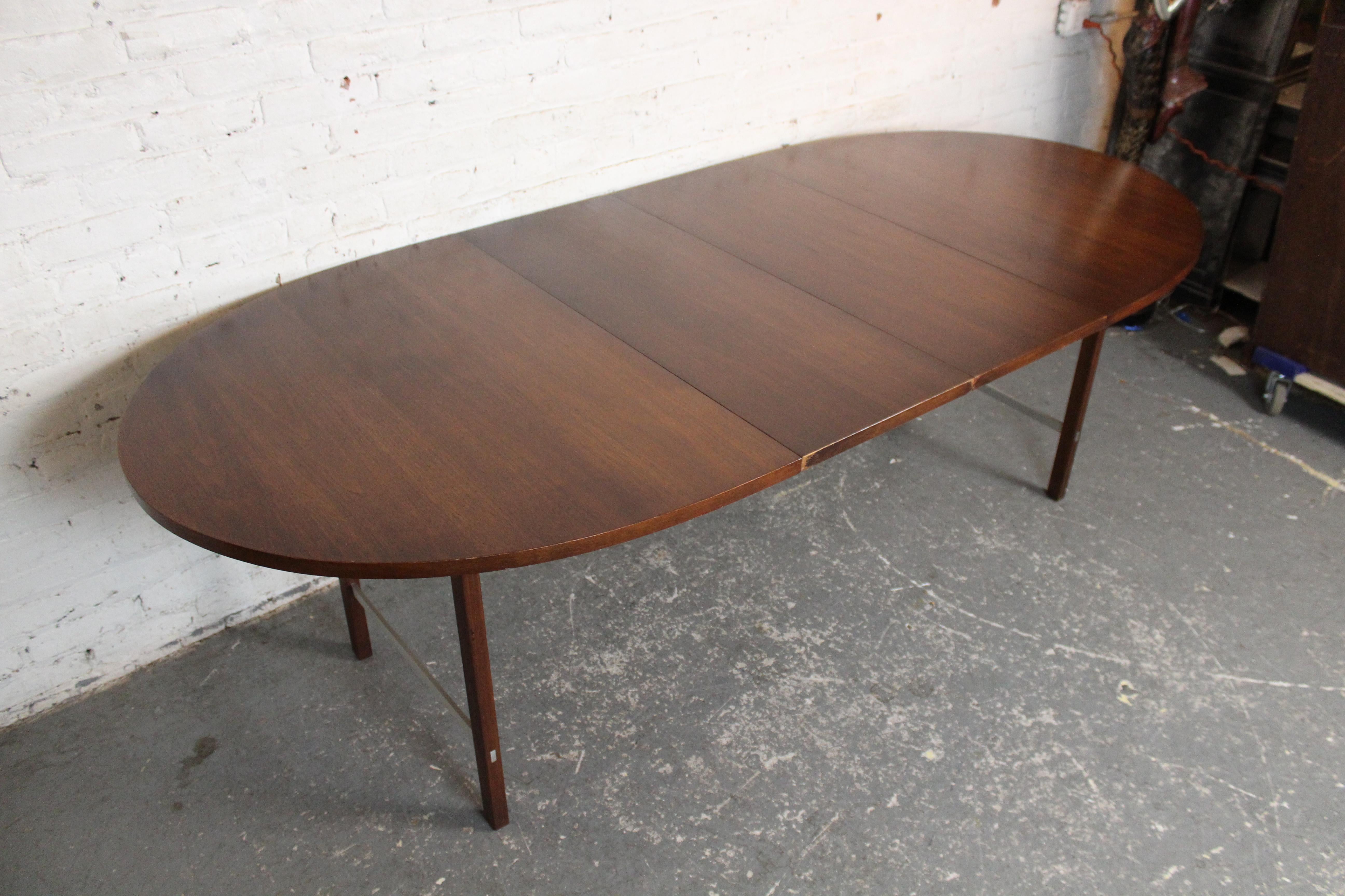 A classic Mid-Century Modern dining table by Paul McCobb for Calvin Furniture, featuring a rich walnut top and clean, minimalist lines characteristic of McCobb’s work. The table extends with two leaves, expanding from a compact size to a generous