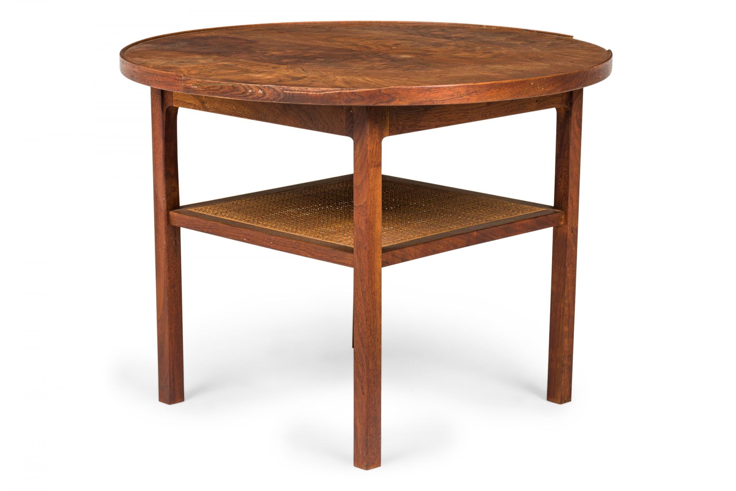 American Mid-Century end / side table with a circular top, walnut frame, and square caned lower stretcher shelf, resting on four walnut dowel legs. (PAUL MCCOBB FOR CALVIN FURNITURE COMPANY)
