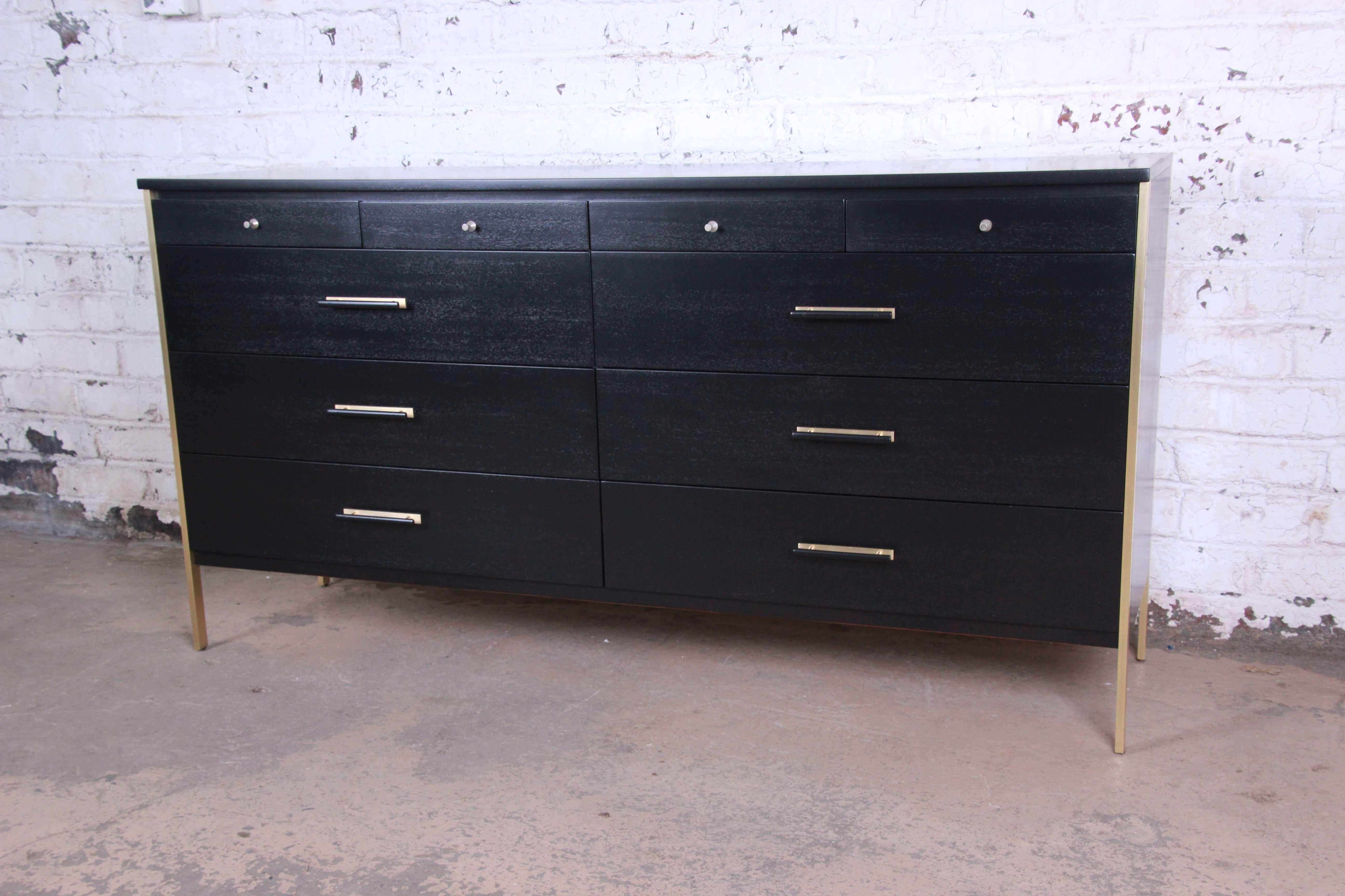 Offering a stunning ebonized Paul McCobb for Calvin Furniture ten-drawer long dresser. The dresser distinguished brass legs and accents offering ample room for storage. The top of the dresser offers four smaller drawers for storage and organization