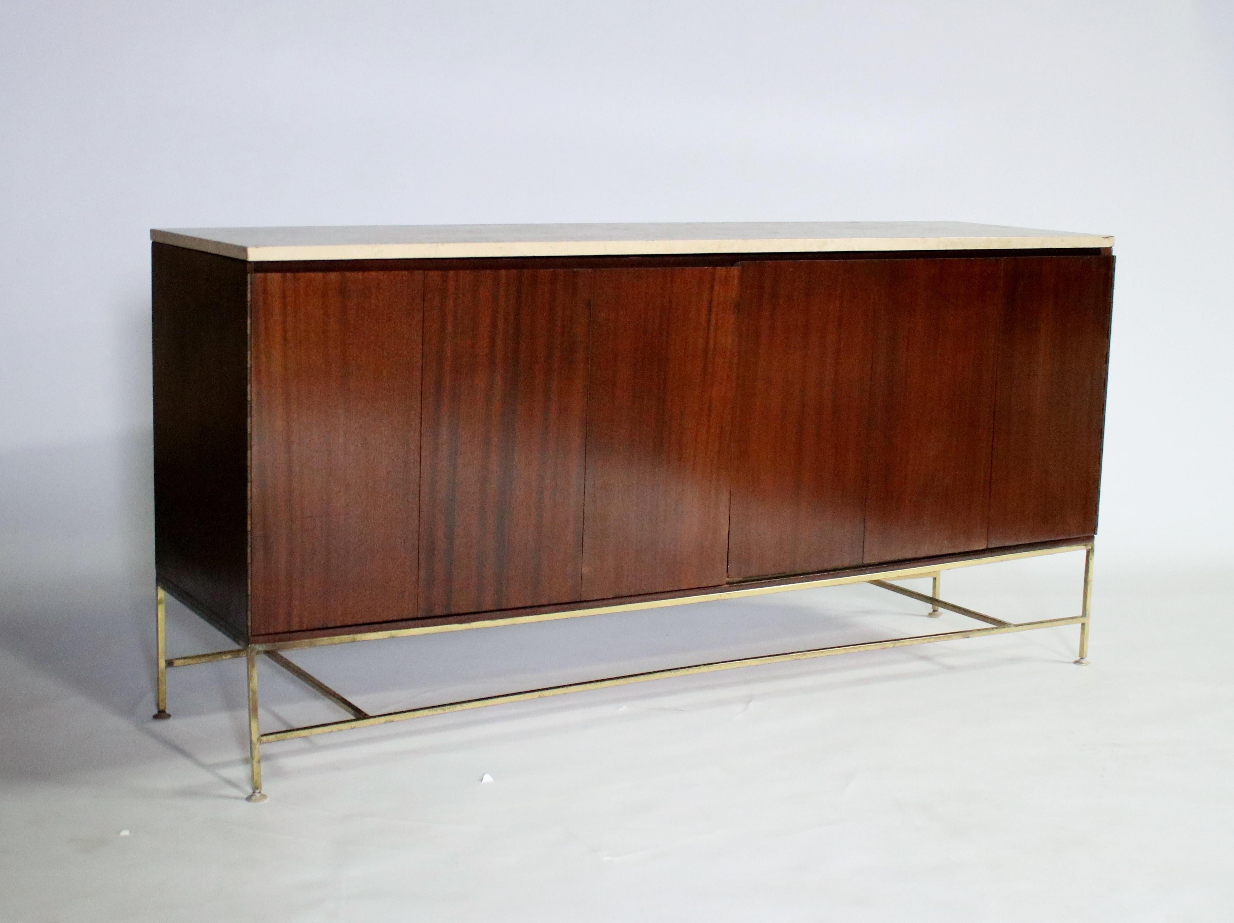 Paul McCobb from Calvin Irwin collection sideboard in original mahogany wood with brass stretchers and a travertine stone top. Accordion-style doors open to reveal a single shelf on the left side while the right side opens to 4 pull-out shelves.