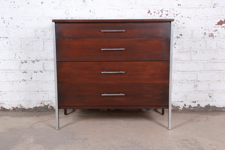 An exceptional Mid-Century Modern bachelor chest designed by Paul McCobb for his Linear Group line for Calvin Furniture. The dresser features beautiful walnut wood grain with aluminum trim. It offers good storage, with four dovetailed drawers each