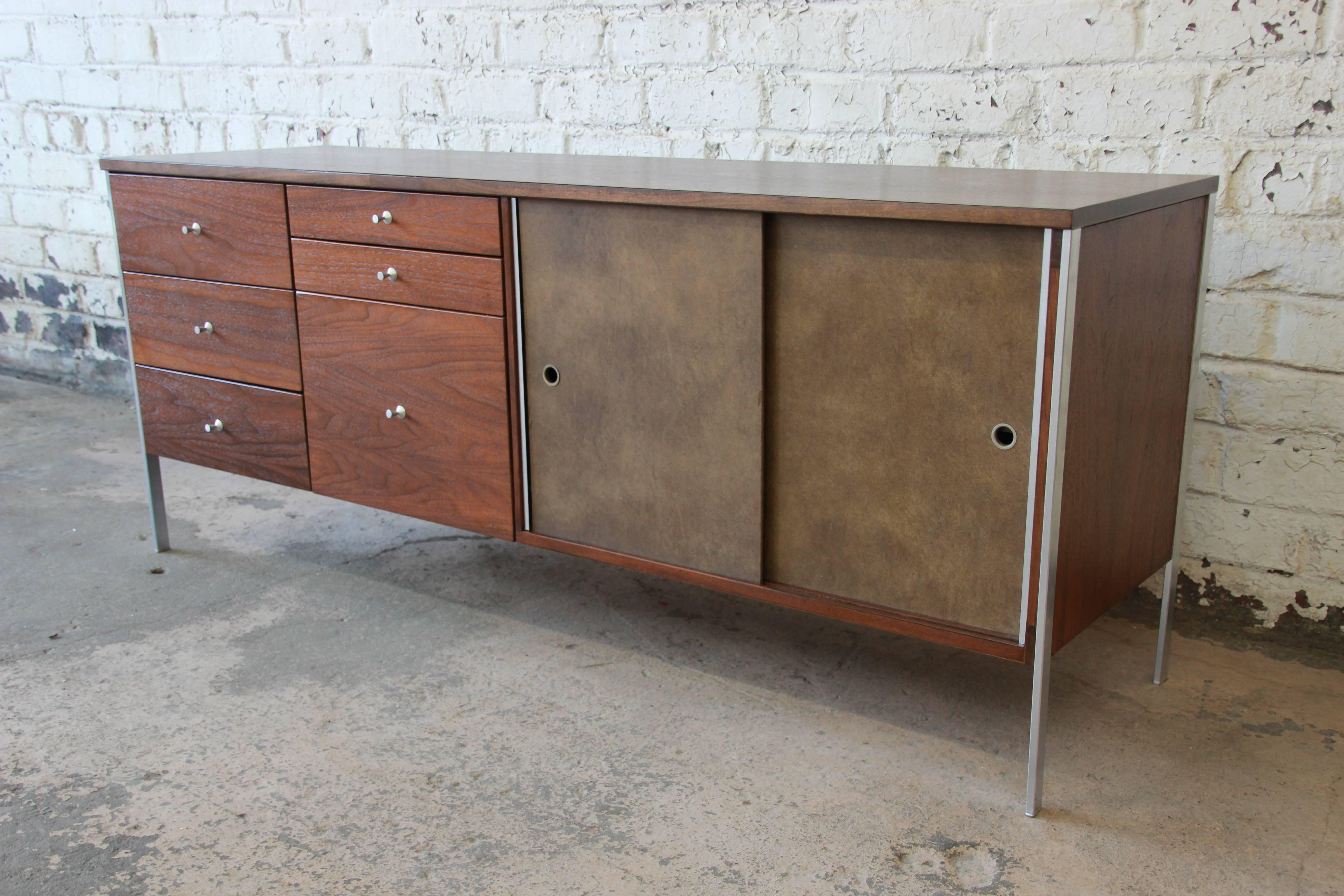 A rare and exceptional Mid-Century Modern walnut credenza designed by Paul McCobb for his 1957 Area Plan Units line. The credenza features gorgeous walnut wood grain and sleek aluminium legs. To the left are six drawers of various sizes, with