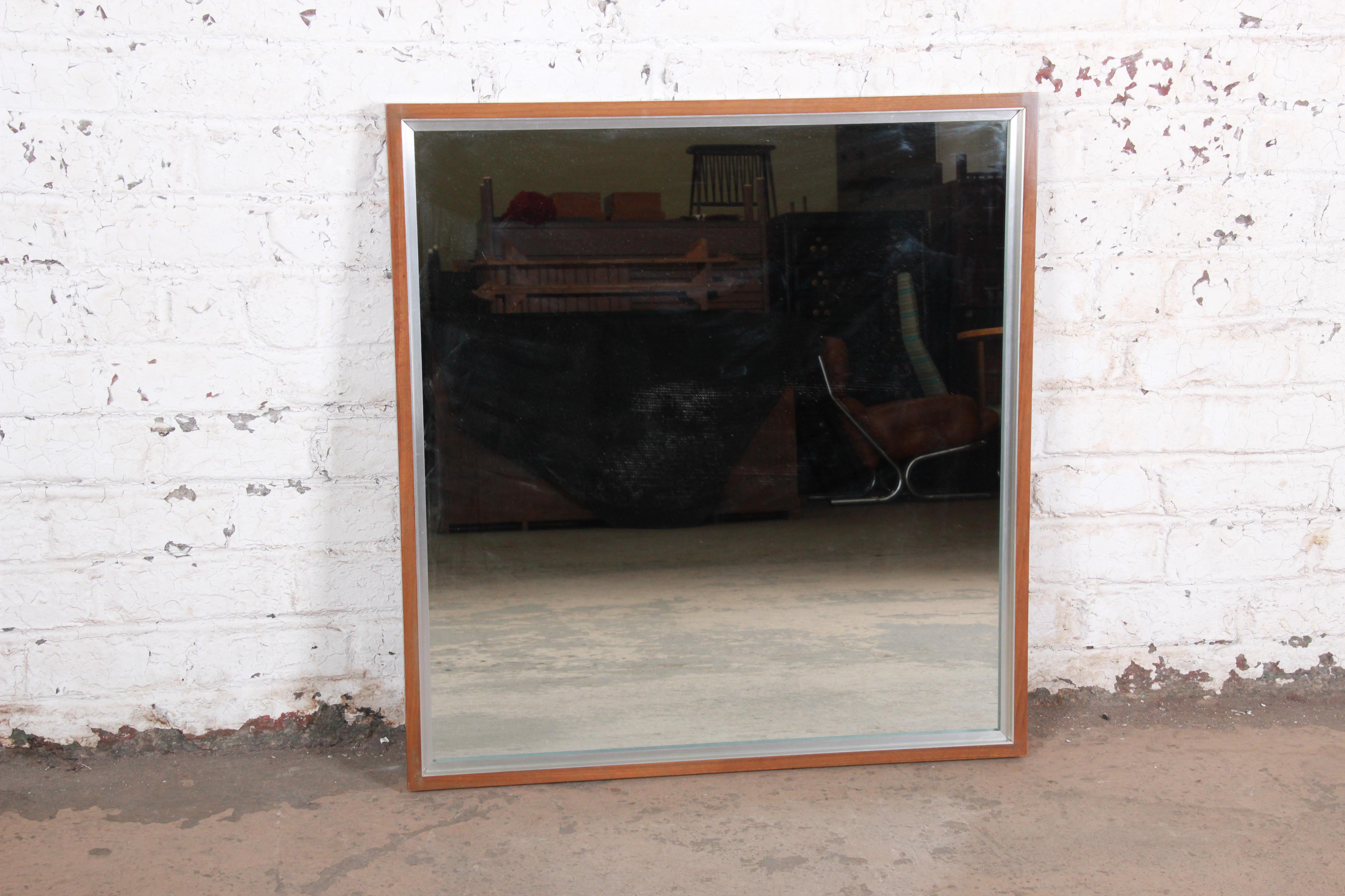 A gorgeous Mid-Century Modern wall mirror designed by Paul McCobb for his Linear Group line for Calvin Furniture. The mirror features a heavy walnut frame with aluminum trim. Can be hung vertically or horizontally. The mirror is in very good