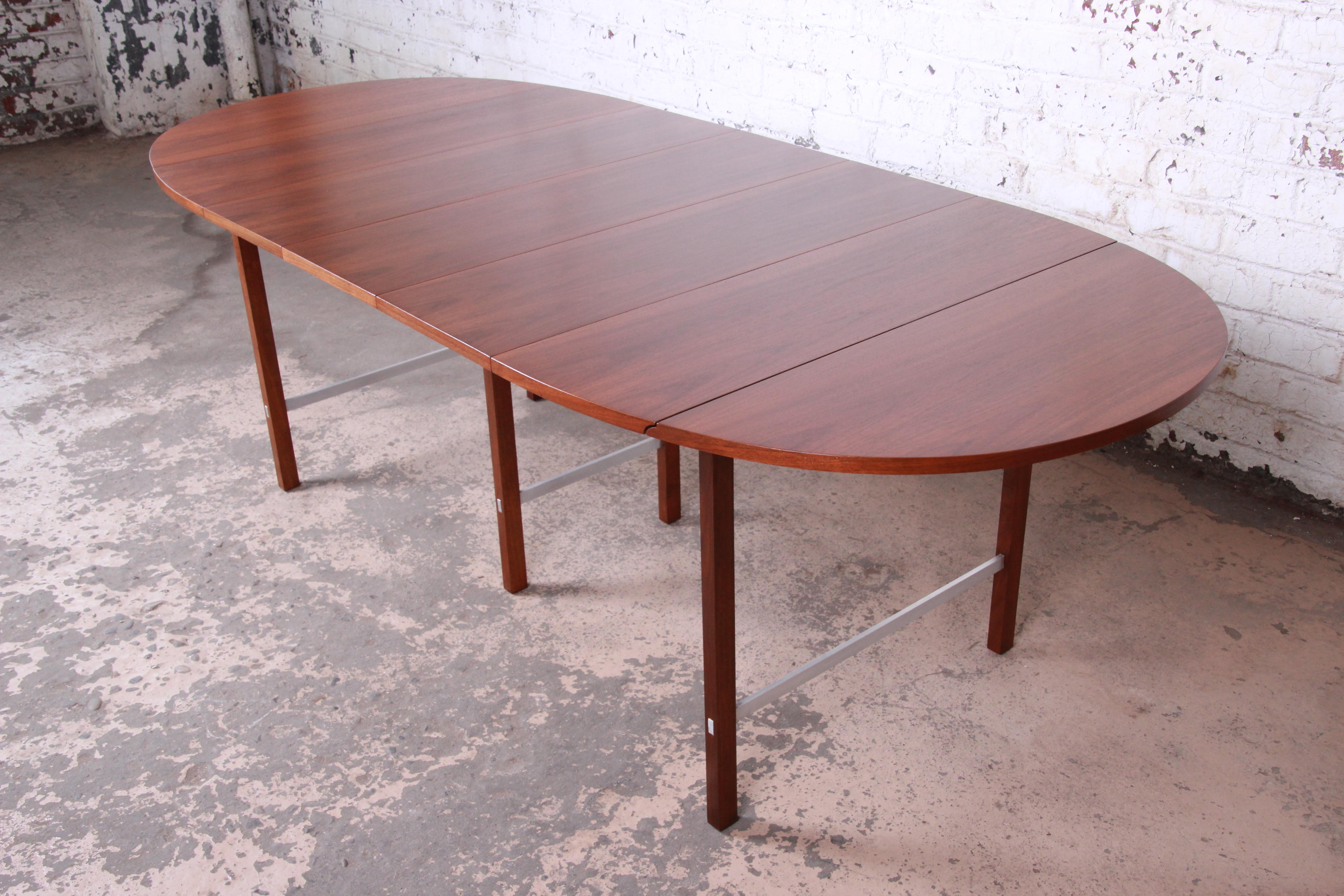 An exceptional Mid-Century Modern walnut extension drop-leaf dining table designed by Paul McCobb for Calvin Furniture. The table features stunning walnut wood grain and aluminum stretchers. It has clean midcentury lines--an excellent example of