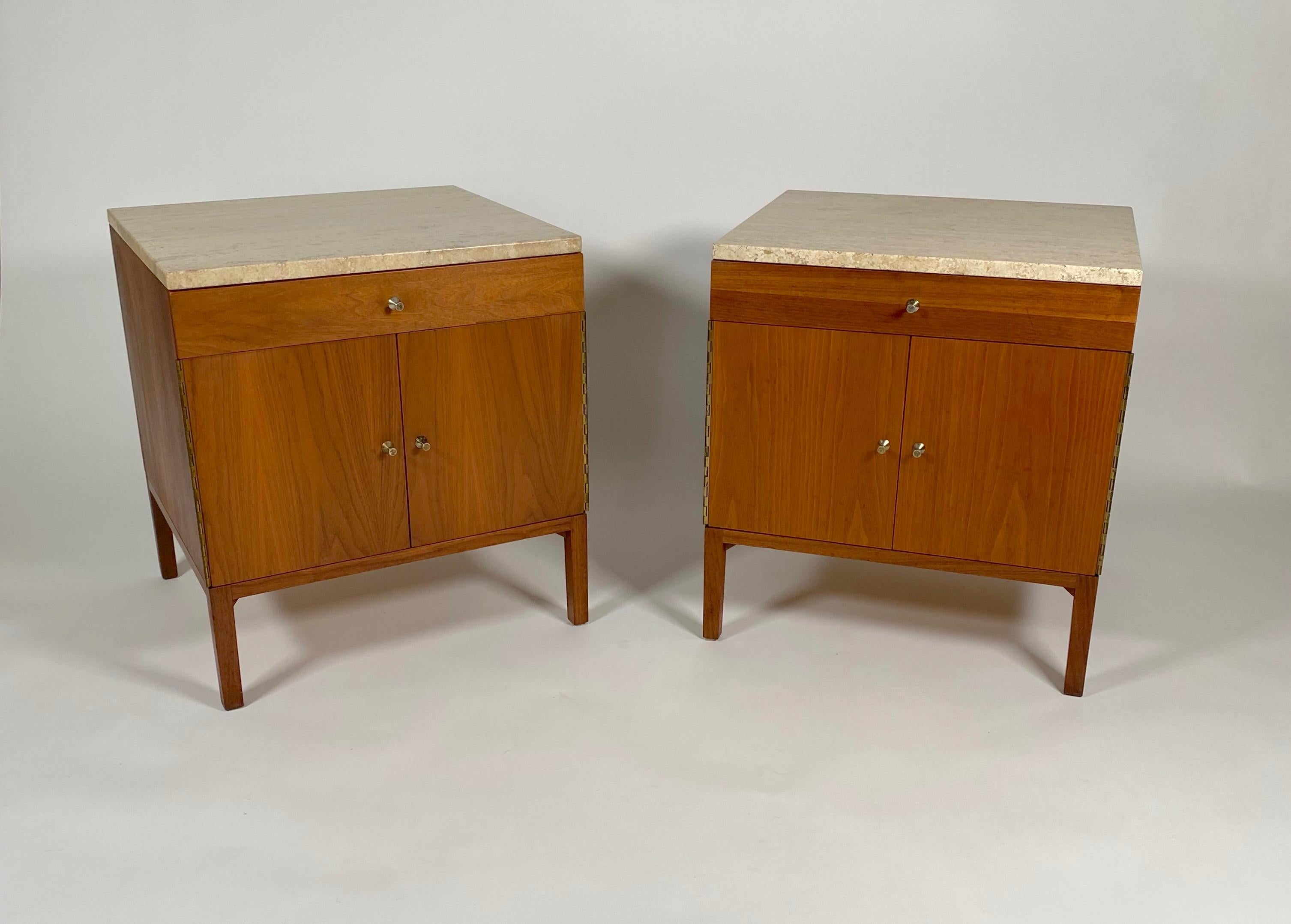 Pair of Paul McCobb for Calvin nightstands in walnut with travertine tops. Having shallow profile top drawers with a two door bottom cabinet with an adjustable shelf, conical pulls on the drawers and doors. The walnut has a rich color and a