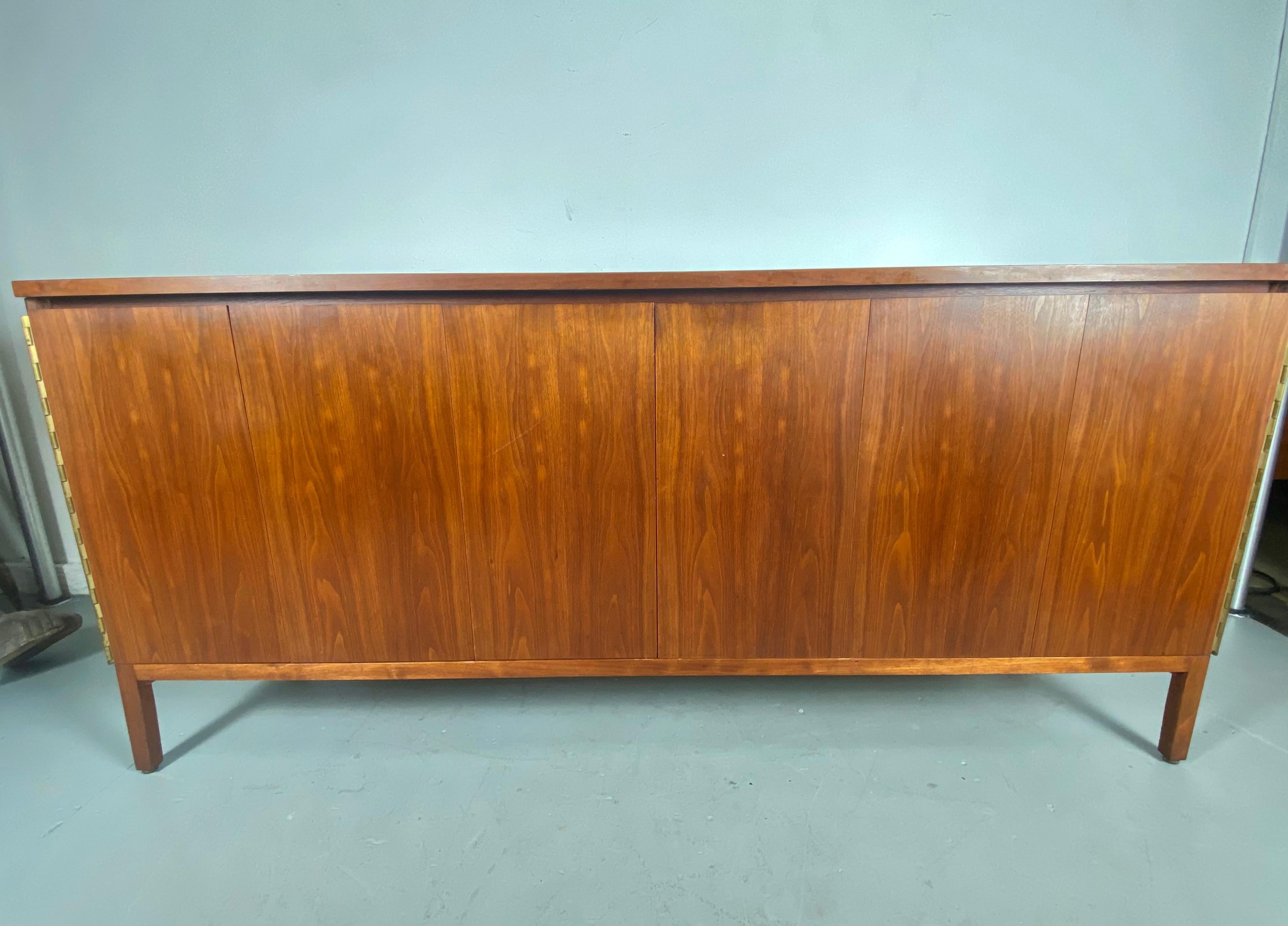 Paul McCobb for Calvin sideboard ,server, credenza with Dual Tri-Fold Doors. Stunning grained walnut, Simple, understated elegance. Piano-hinge trifold doors, finished back, brass detailing, Hand delivery avail to New York City or anywhere en route