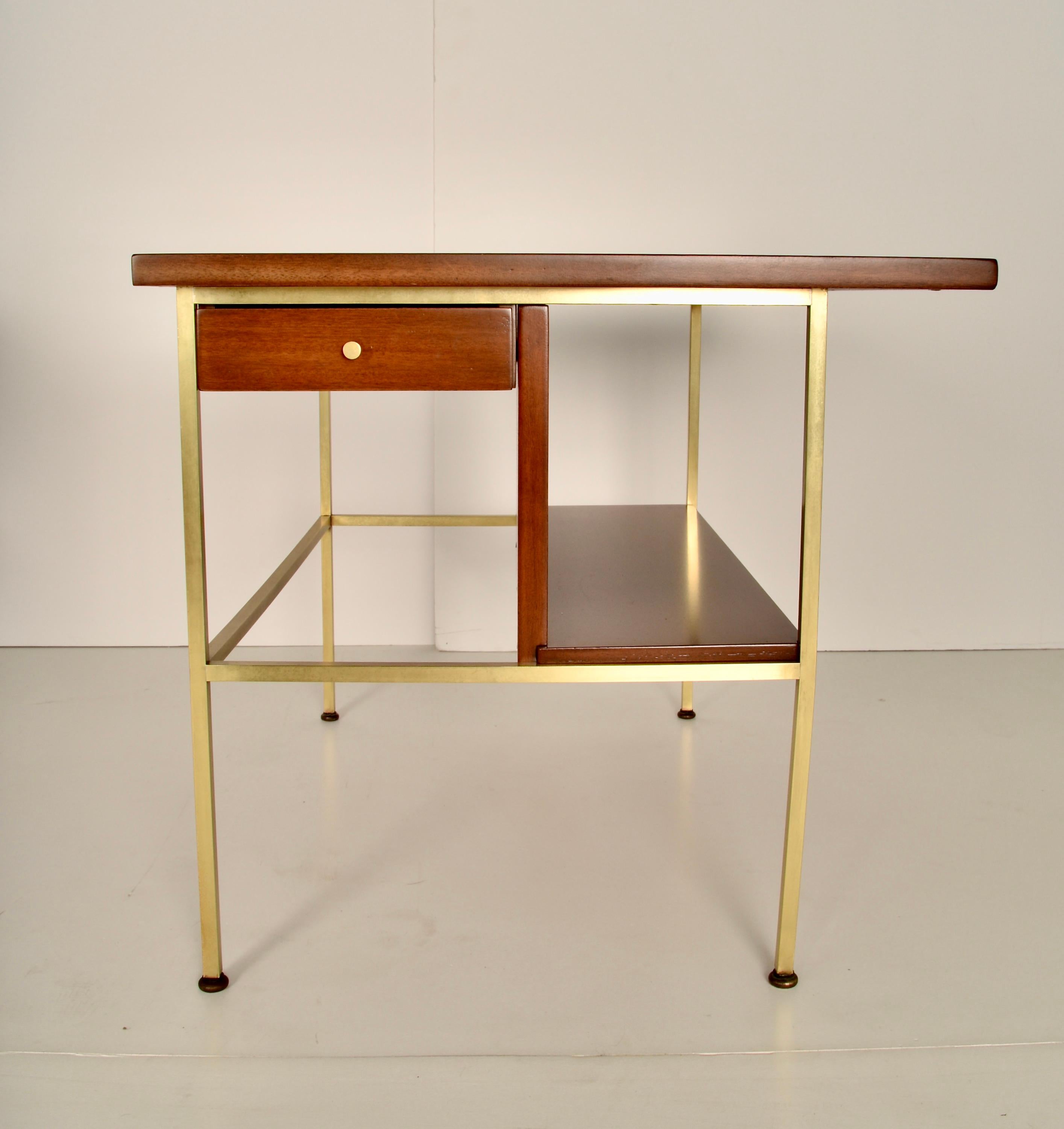 A fine pair of side tables from the Irwin Collection, designed by Paul McCobb for Calvin Furniture in the 1950s. Each of the tables features a single drawer and an open shelf in walnut, along with signature brass legs. These tables have been fully