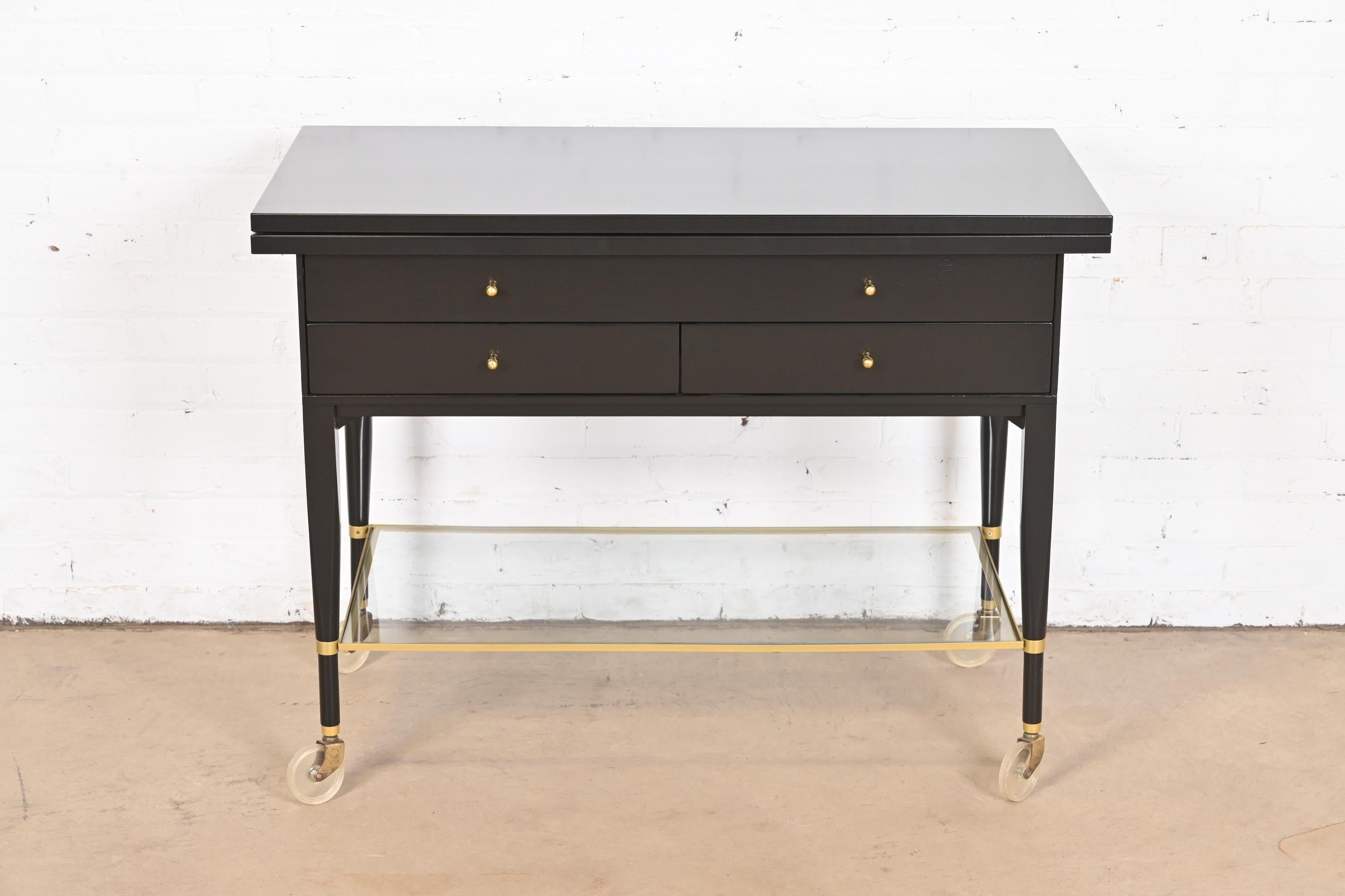 An exceptional Mid-Century Modern flip top extension rolling bar cart server

By Paul McCobb for Directional and produced by Calvin Furniture

USA, 1950s

Black lacquered mahogany, with brass hardware and stretchers, and lower glass