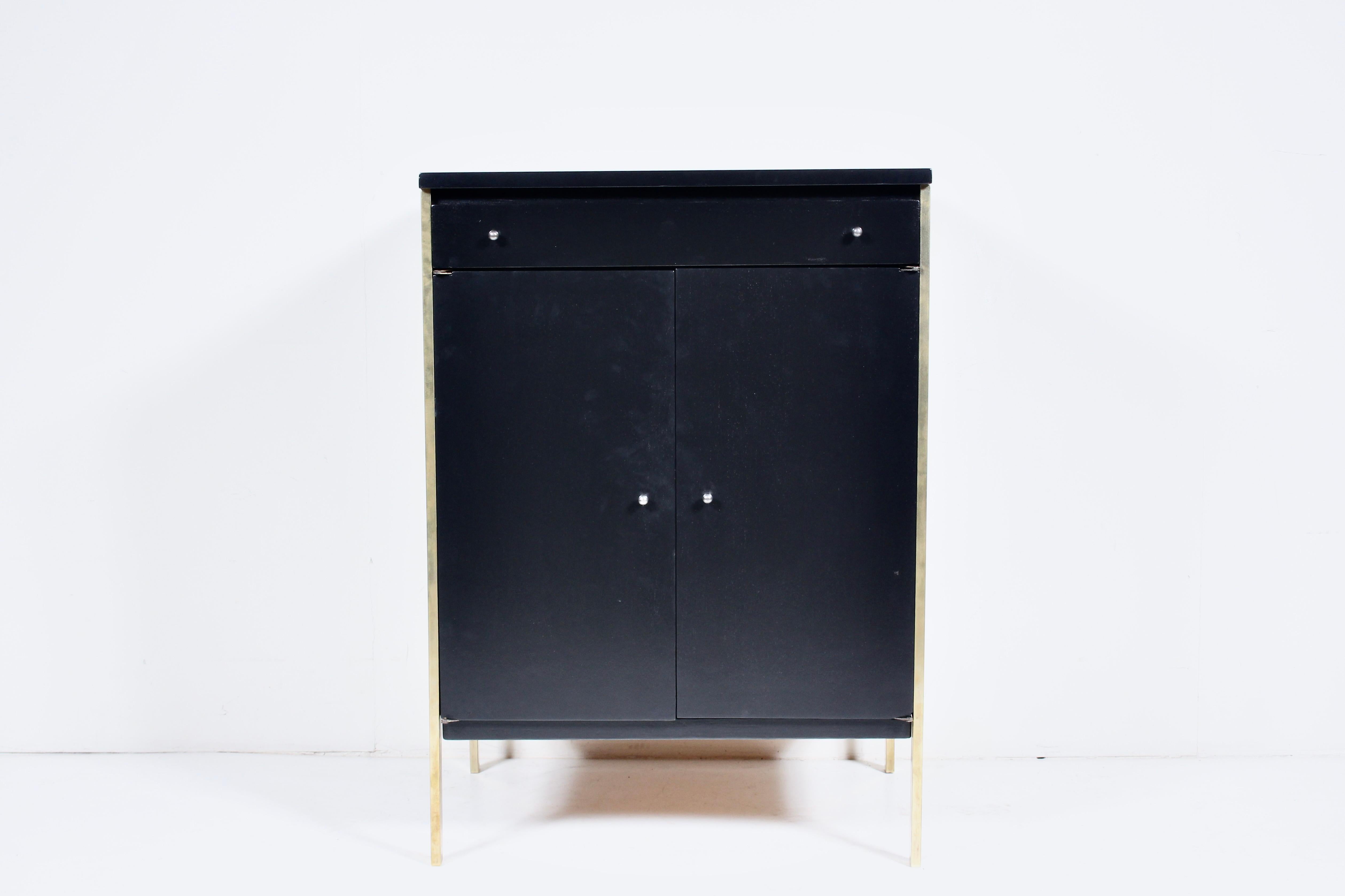Paul McCobb per Directional #7026 Armadio a due ante nero con cassetto. Il mobile rettangolare a due ante a battente, con cassetto superiore e ripiano interno regolabile, è stato restaurato e riverniciato, con gambe in ottone riflettente e grandi
