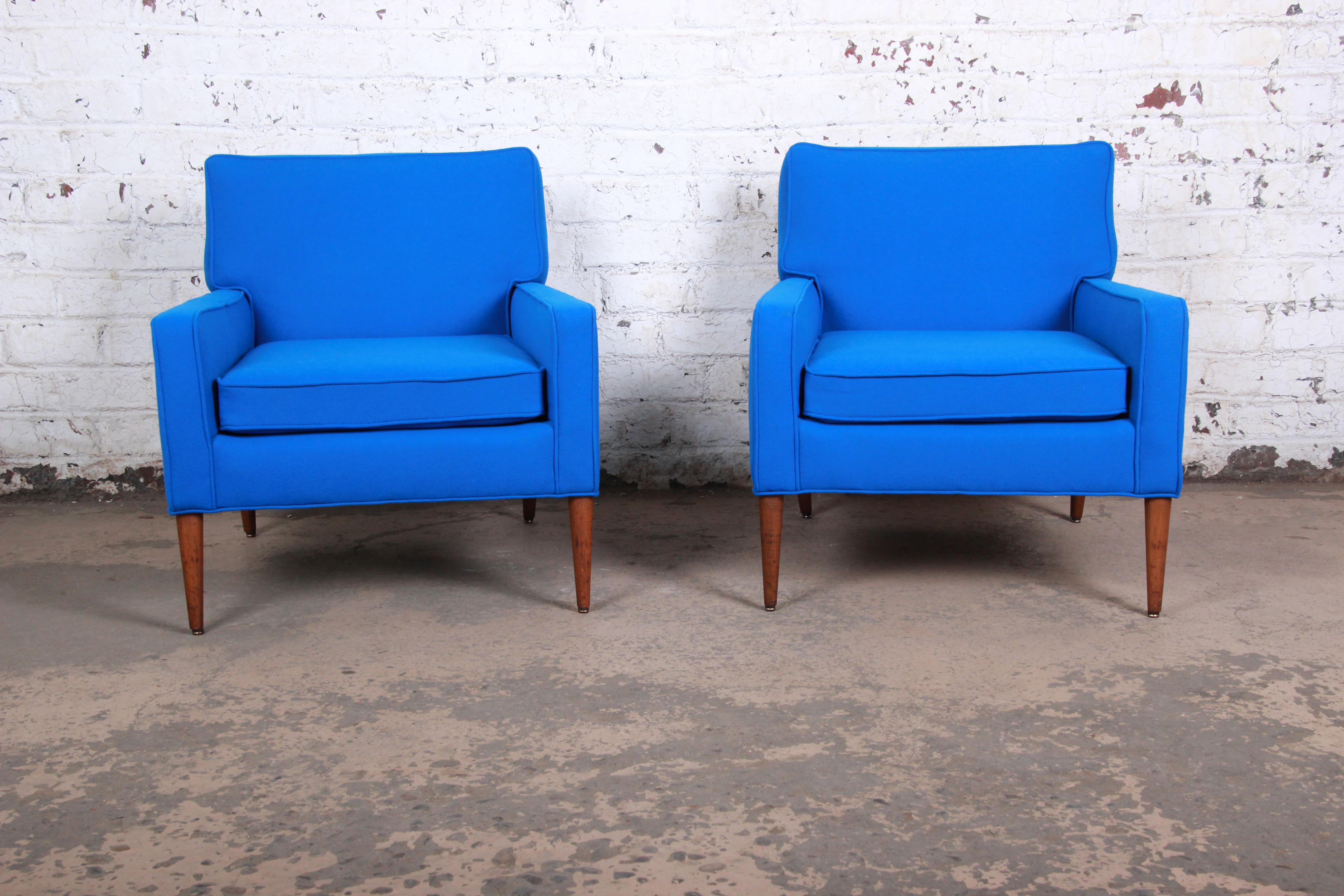 An exceptional pair of Mid-Century Modern lounge chairs designed by Paul McCobb for Directional and produced by Custom Craft. The chairs feature vibrant blue Knoll fabric and sleek solid walnut tapered legs. An excellent example of McCobb's