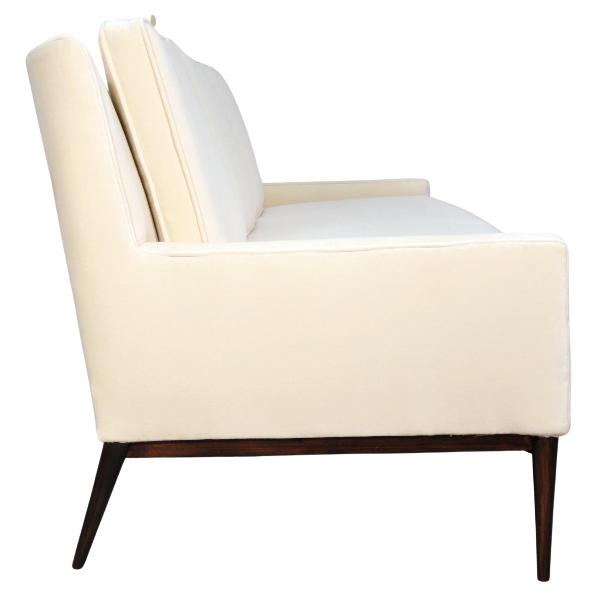 Reupholstered Mid-Century Modern model 1307 light cream velvet sofa by Paul McCobb for Directional. The couch has been recovered in a gorgeous neutral velvet. The sofa features a slight wing back and beautifully sculpted solid mahogany wood base