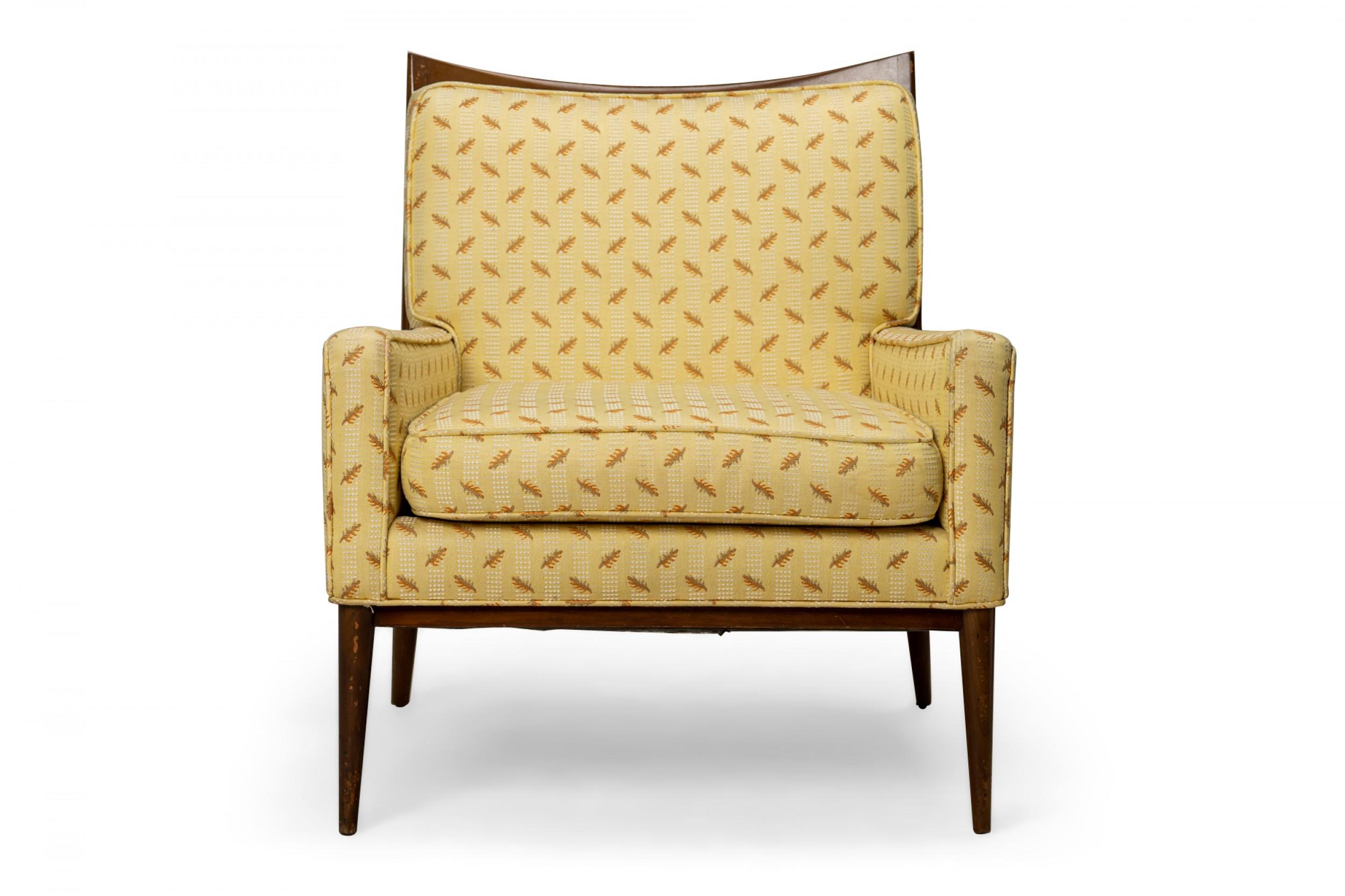 American Mid-Century lounge / armchair with a stained walnut frame with a scooped back rail and yellow fabric upholstery with a small pattern of orange and brown autumn leaves and white dots, resting on four tapered dowel legs. (PAUL MCCOBB FOR