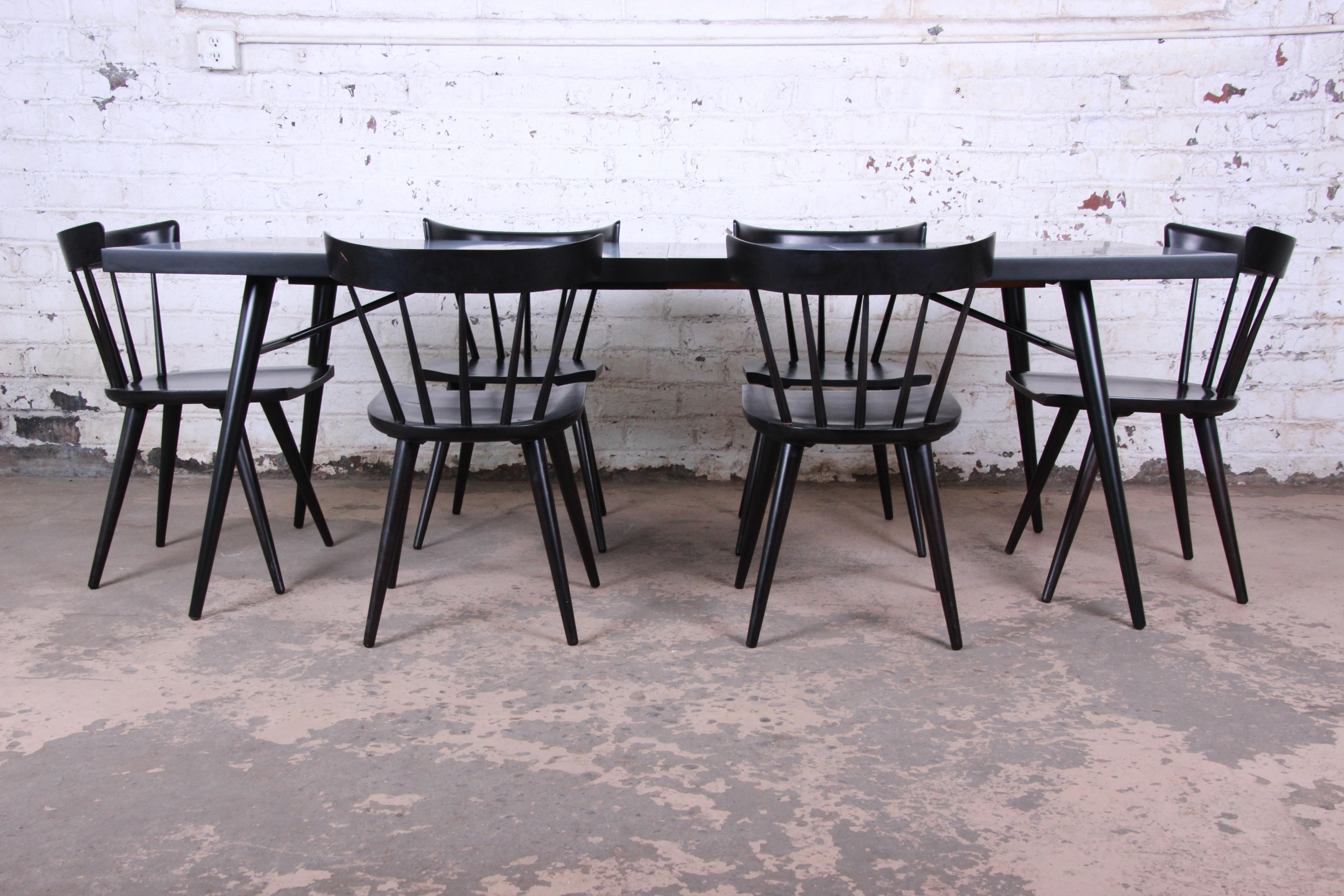Extension dining table and six chairs. The table extends to 84.13 inches with both of the 15 inch leaves in. The table is newly refinished in a sleep black lacquer. The chairs make this distinct McCobb Mid-Century Modern design and perfect set for
