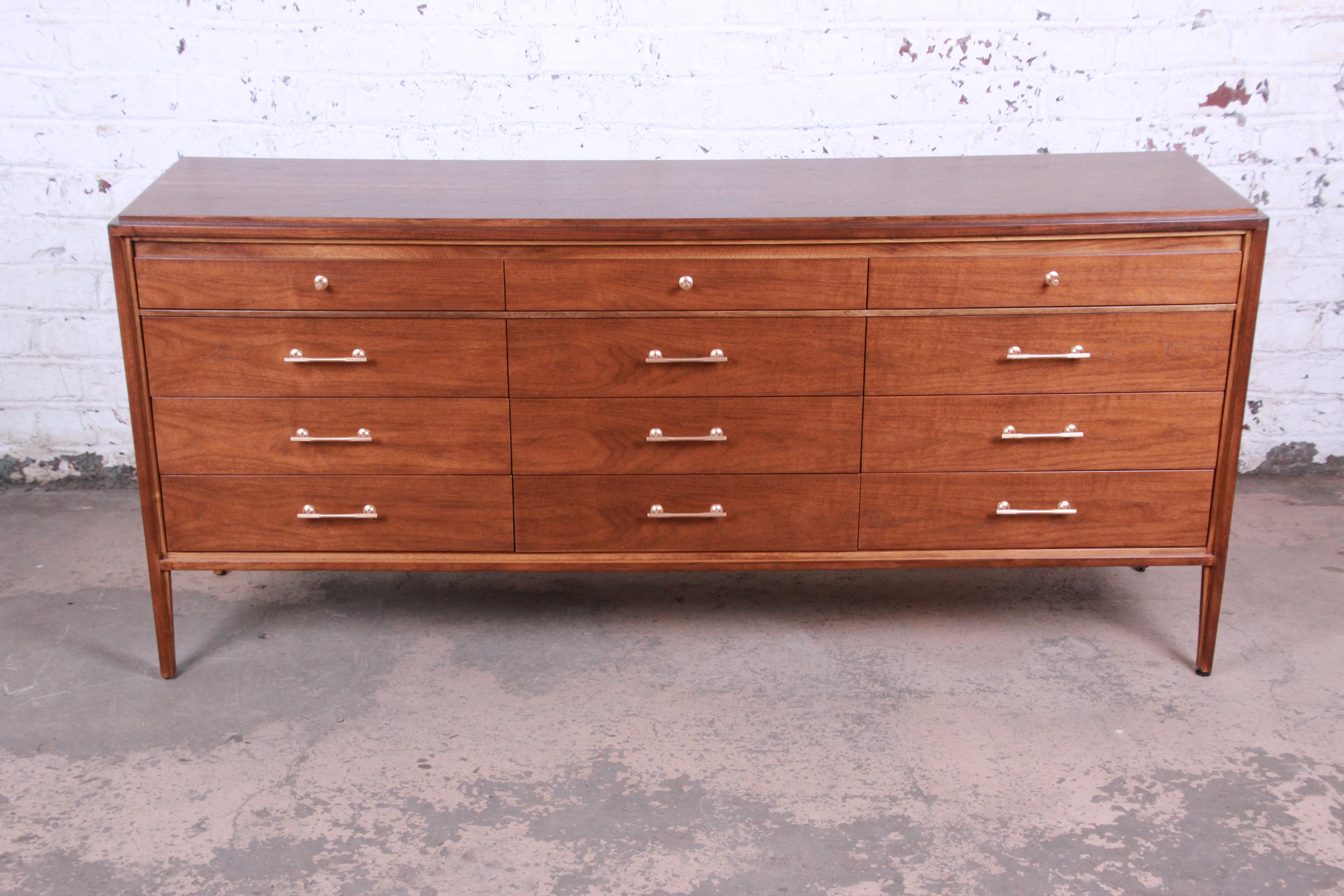 A rare and exceptional twelve-drawer walnut dresser or credenza designed by Paul McCobb for his Grand Rapids Collection for Widdicomb Furniture. The dresser features gorgeous walnut wood grain and Minimalist Mid-Century Modern design. It offers