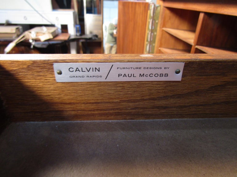 Paul McCobb's gentleman's chest with a fold down mirror. Irwin line for Calvin.
The accordion doors open to 18 shirt shelves and five graduated drawers.

Please confirm item location (NJ or NY).