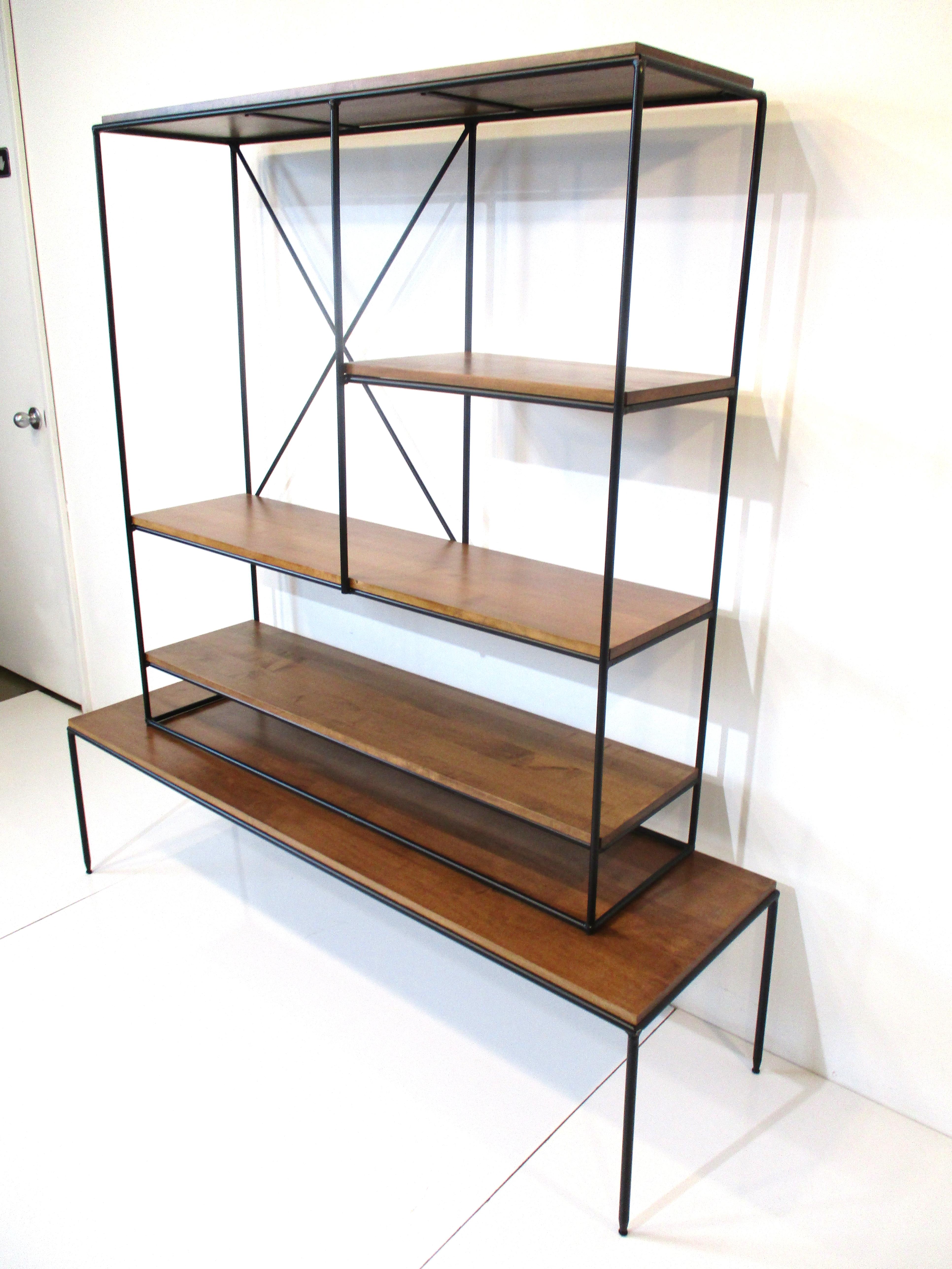 A two piece satin black iron framed bookcase with medium dark solid maple wood shelves . The unit sits on the matching bottom platform giving the piece a open simple , lighter look typical of the other designs from the Planner Group Collection ,